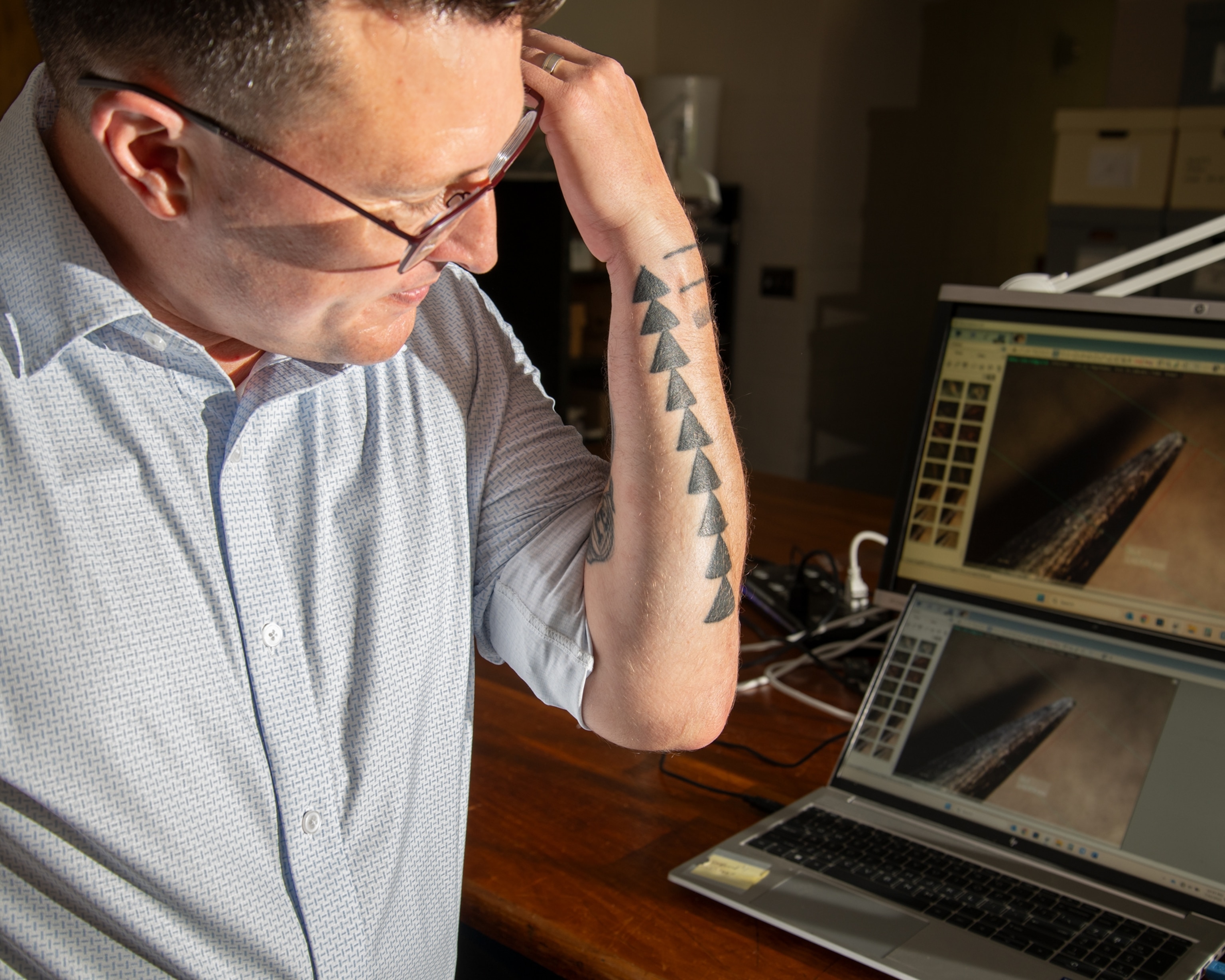 Man looking at his left arm displaying tattoo.