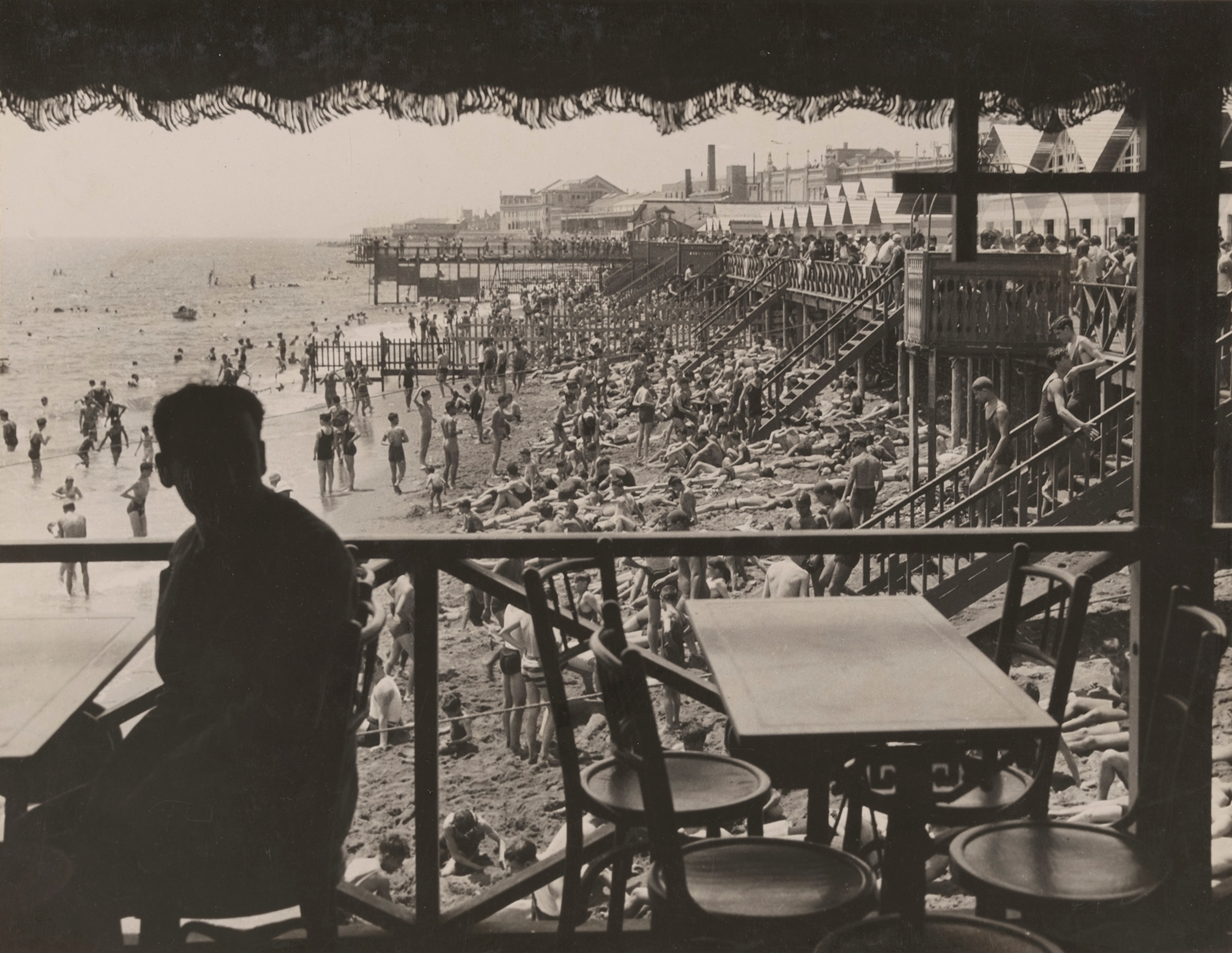 A diner overlooks a crowded beach in the resort city of Barceloneta.