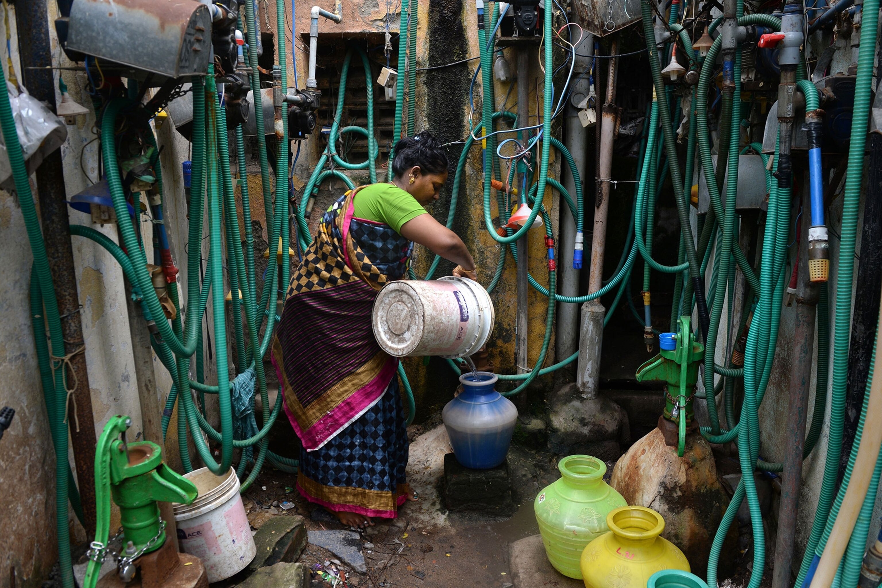 an Indian resident fills a pot with water from a tap at a residential complex in Chennai.