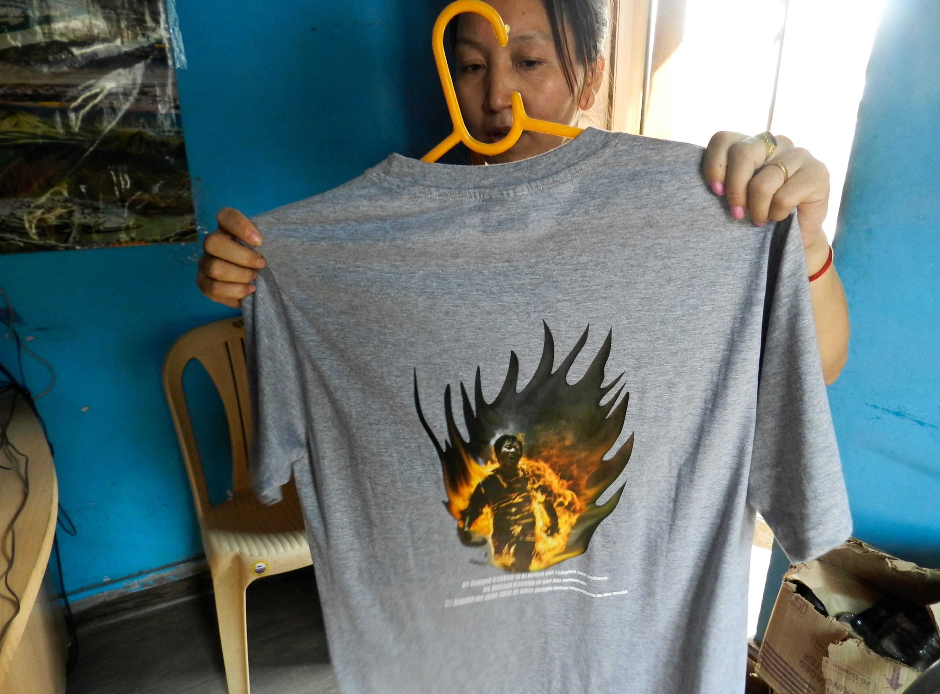 a woman holding a T-shirt with the image of Jamphel Yeshi
