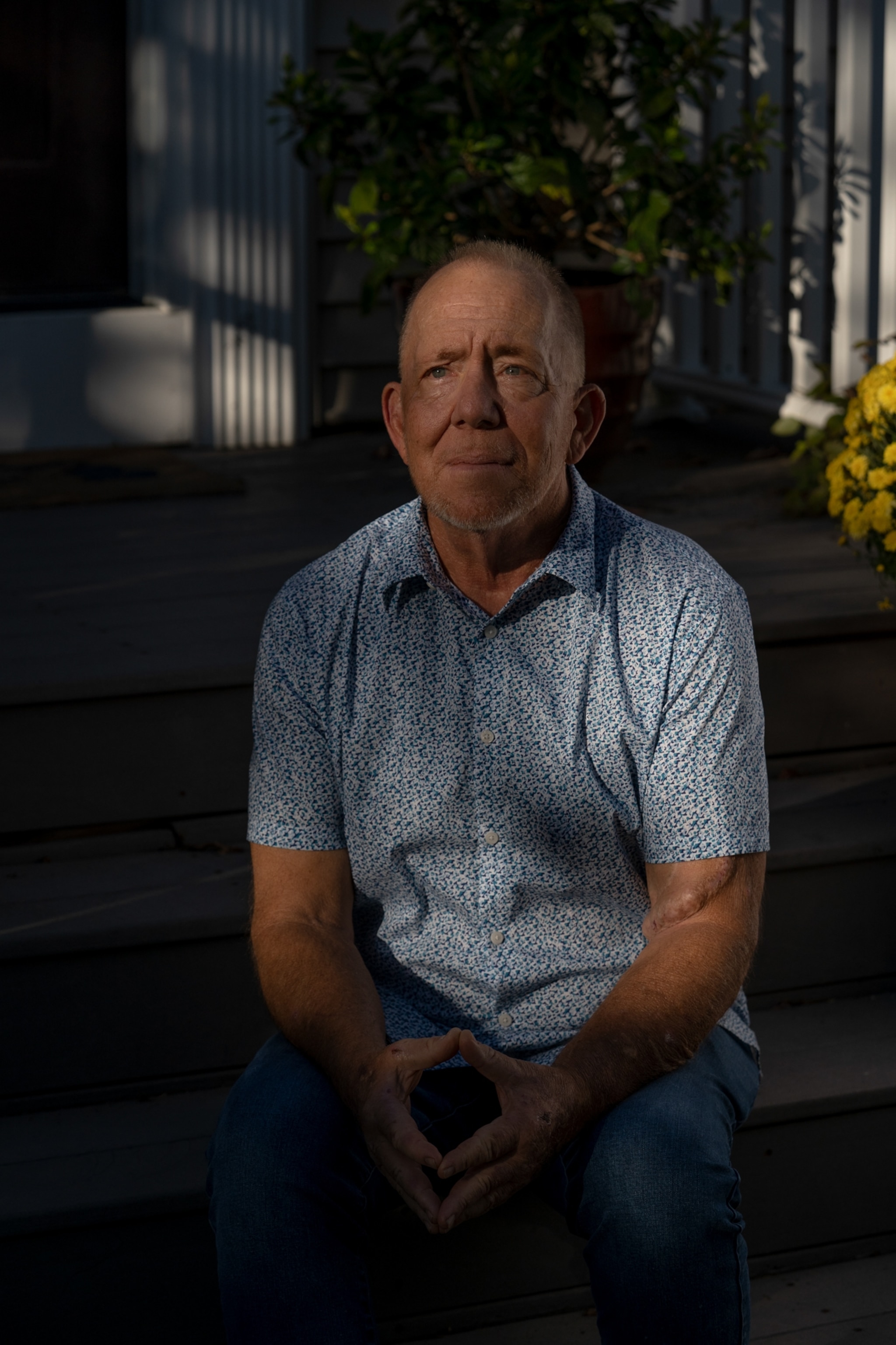 a man sits in his backyard outside his home