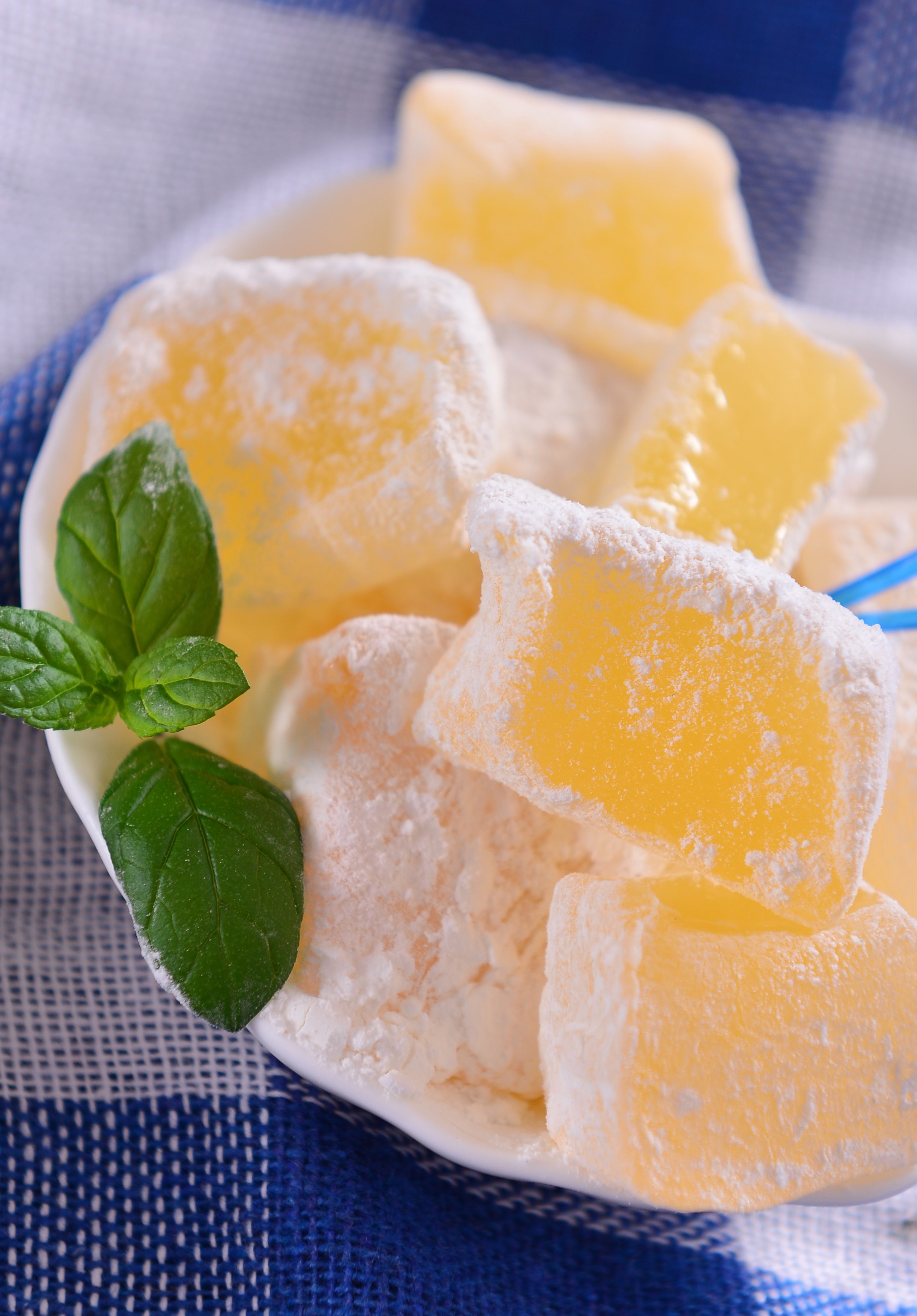 yellow sweet covered in powdered sugar on a blue and white plaid background