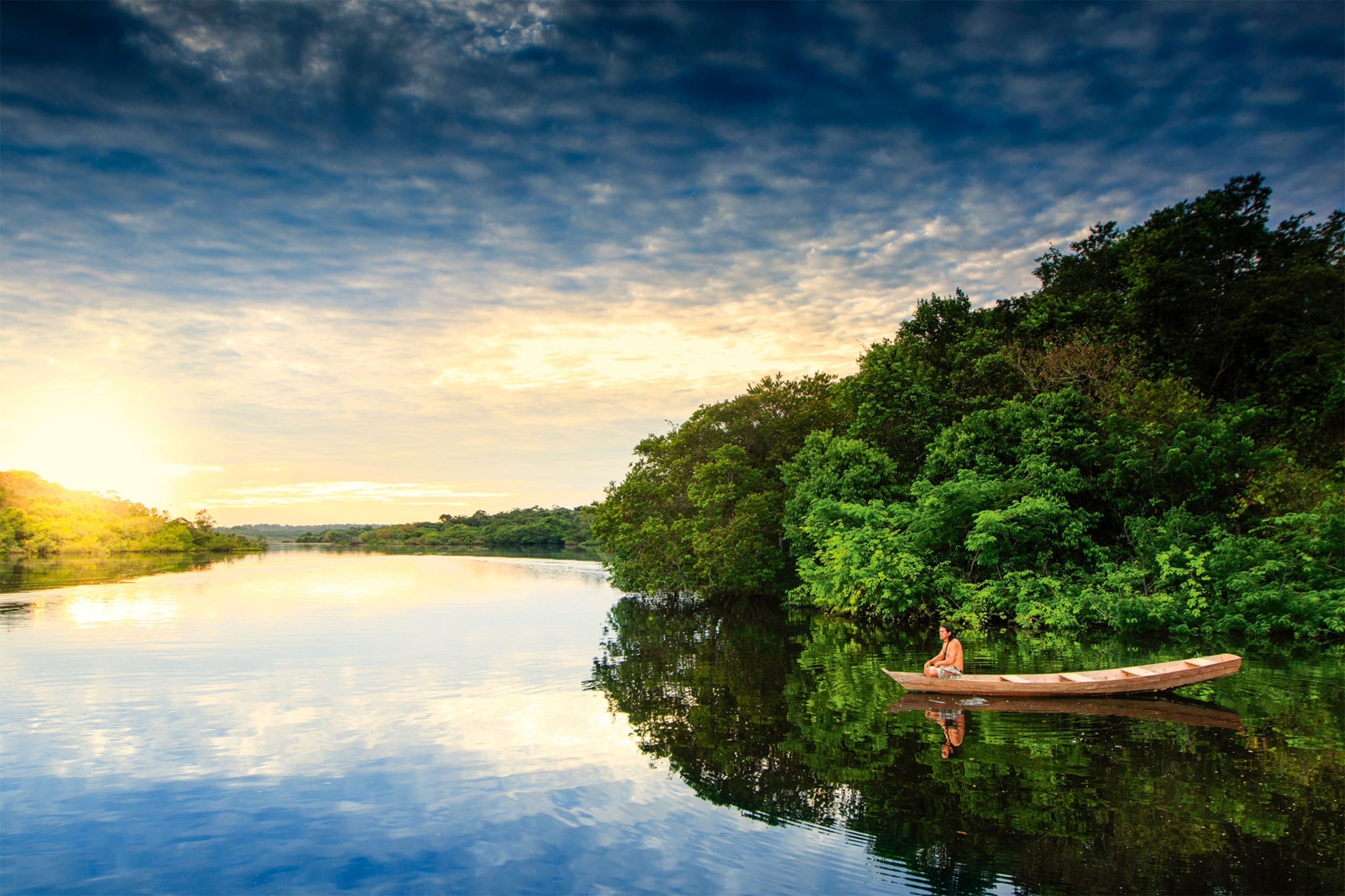 An Indigenous Brazilian rests in a canoe on the Tarumã Mirim River