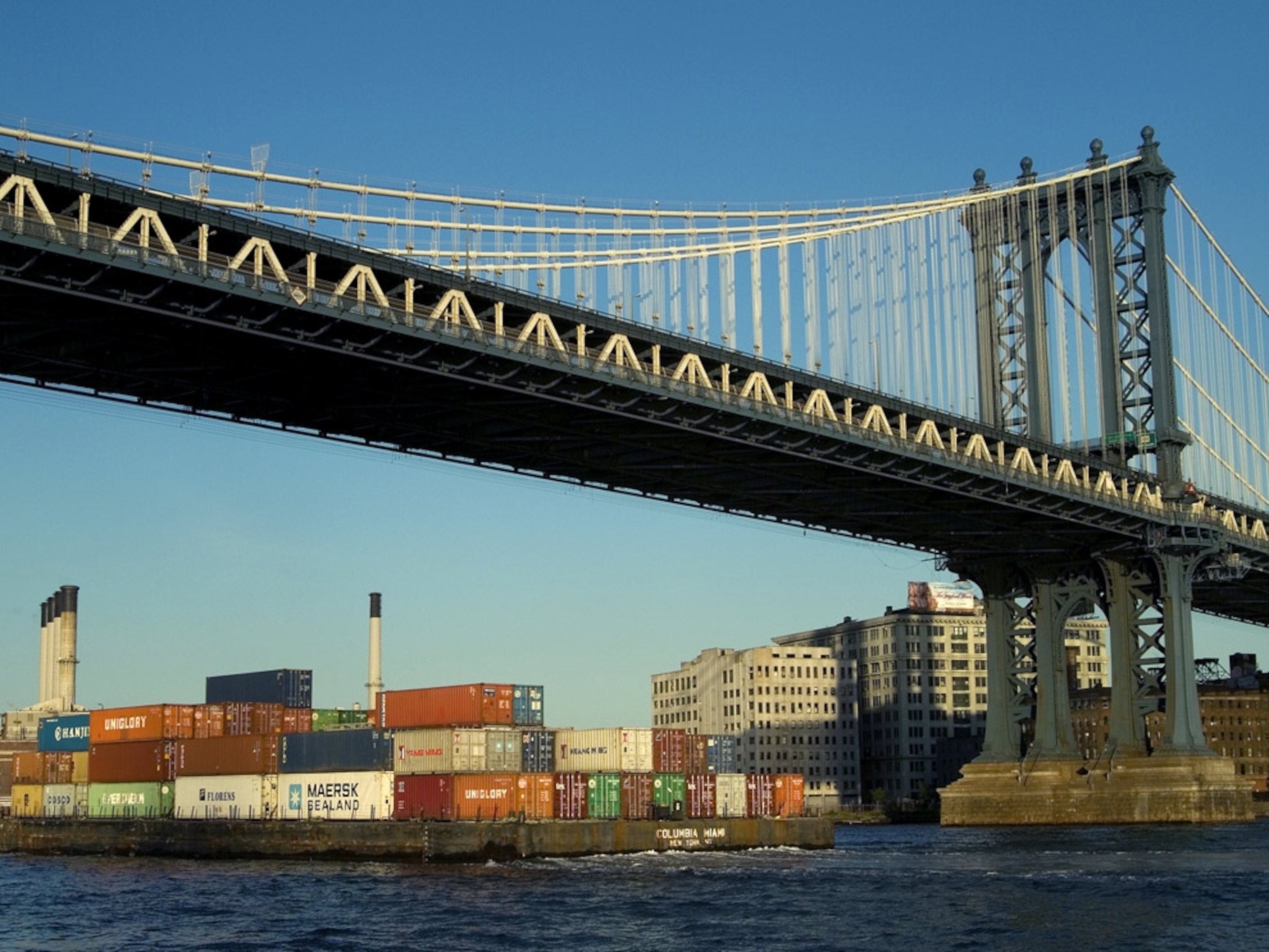 Large container barge passing under the Manhattan Bridge, New York City