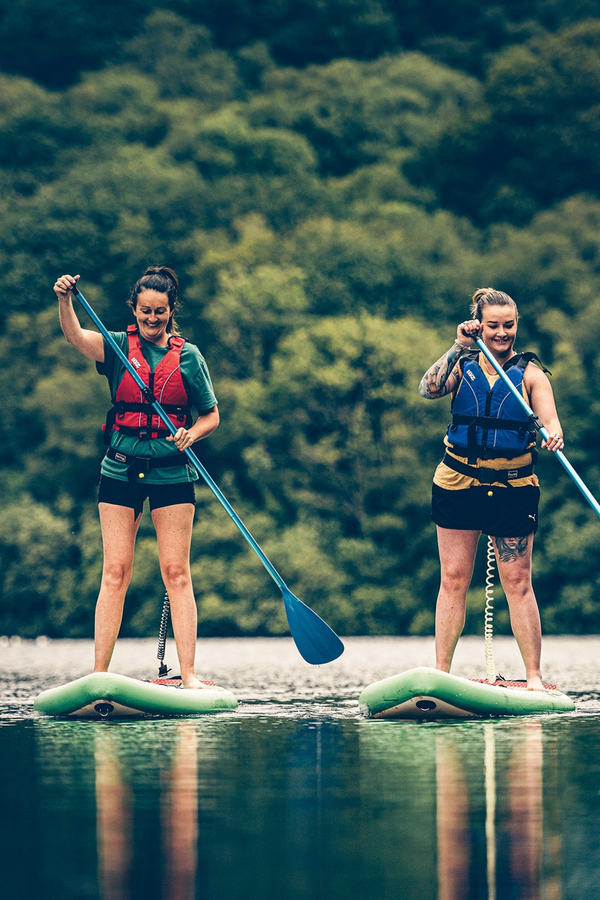 Two young women on paddle boards on a river.