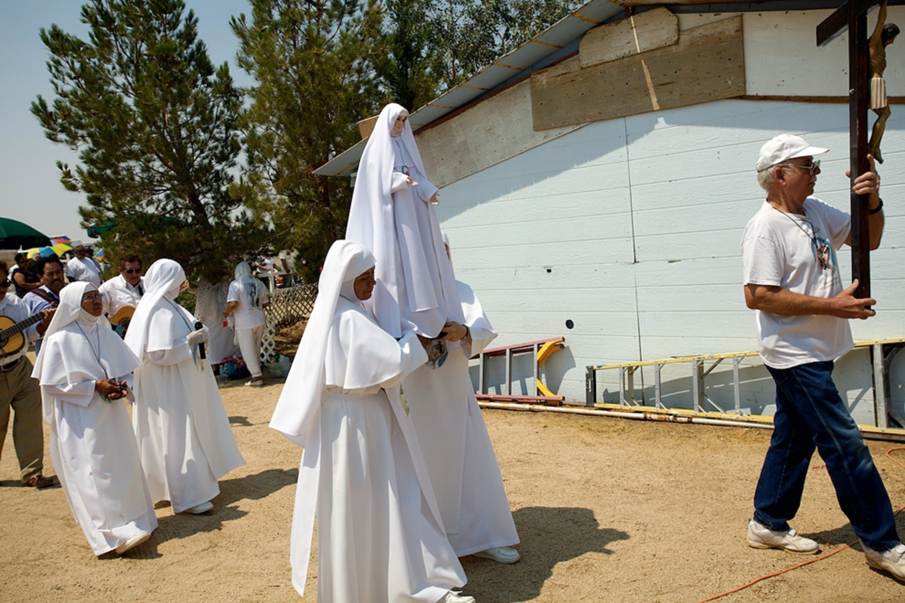 Women in white habits carrying a statue