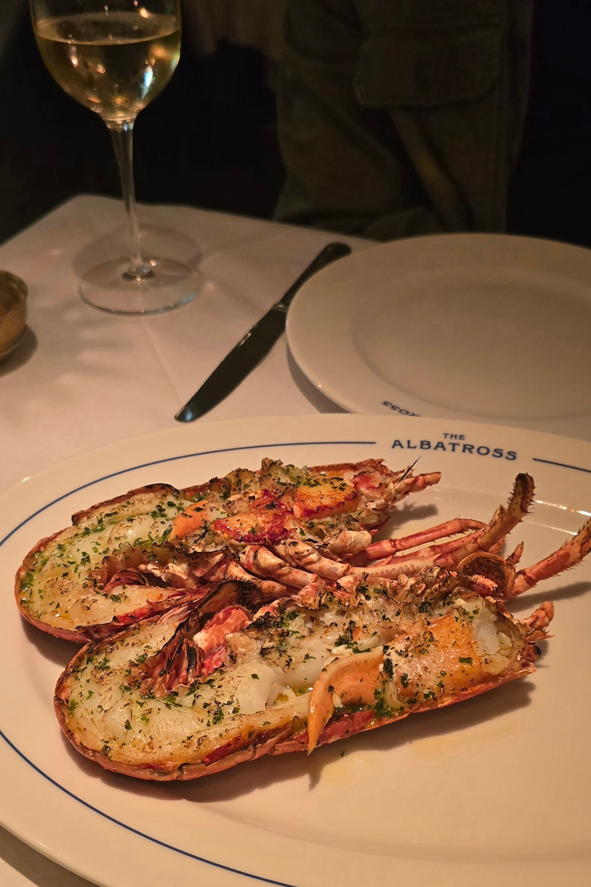 A baked lobster with cheese and herbs in a candle-lit pub.