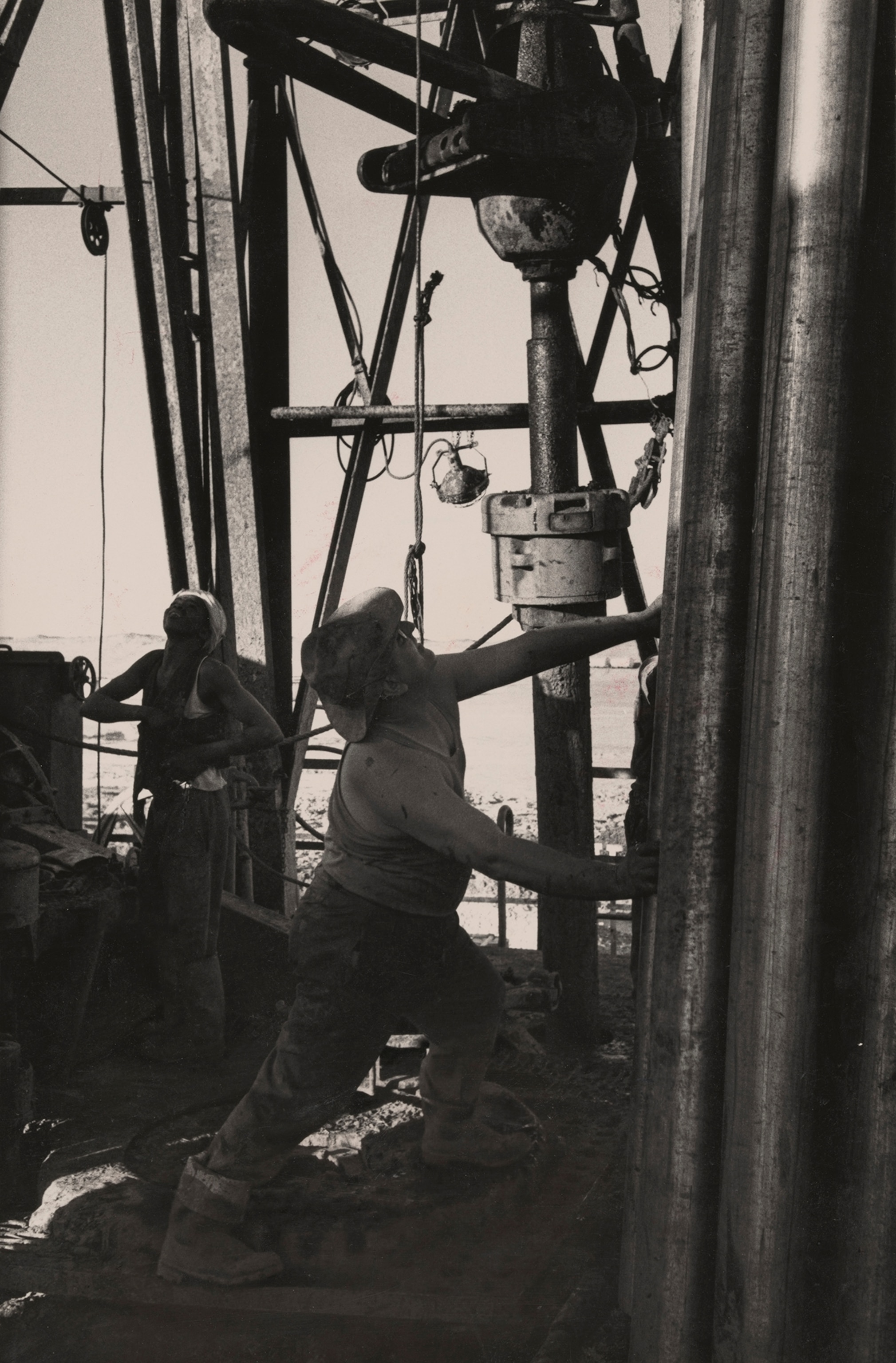 Riggers pull a drill from the borehole of a well