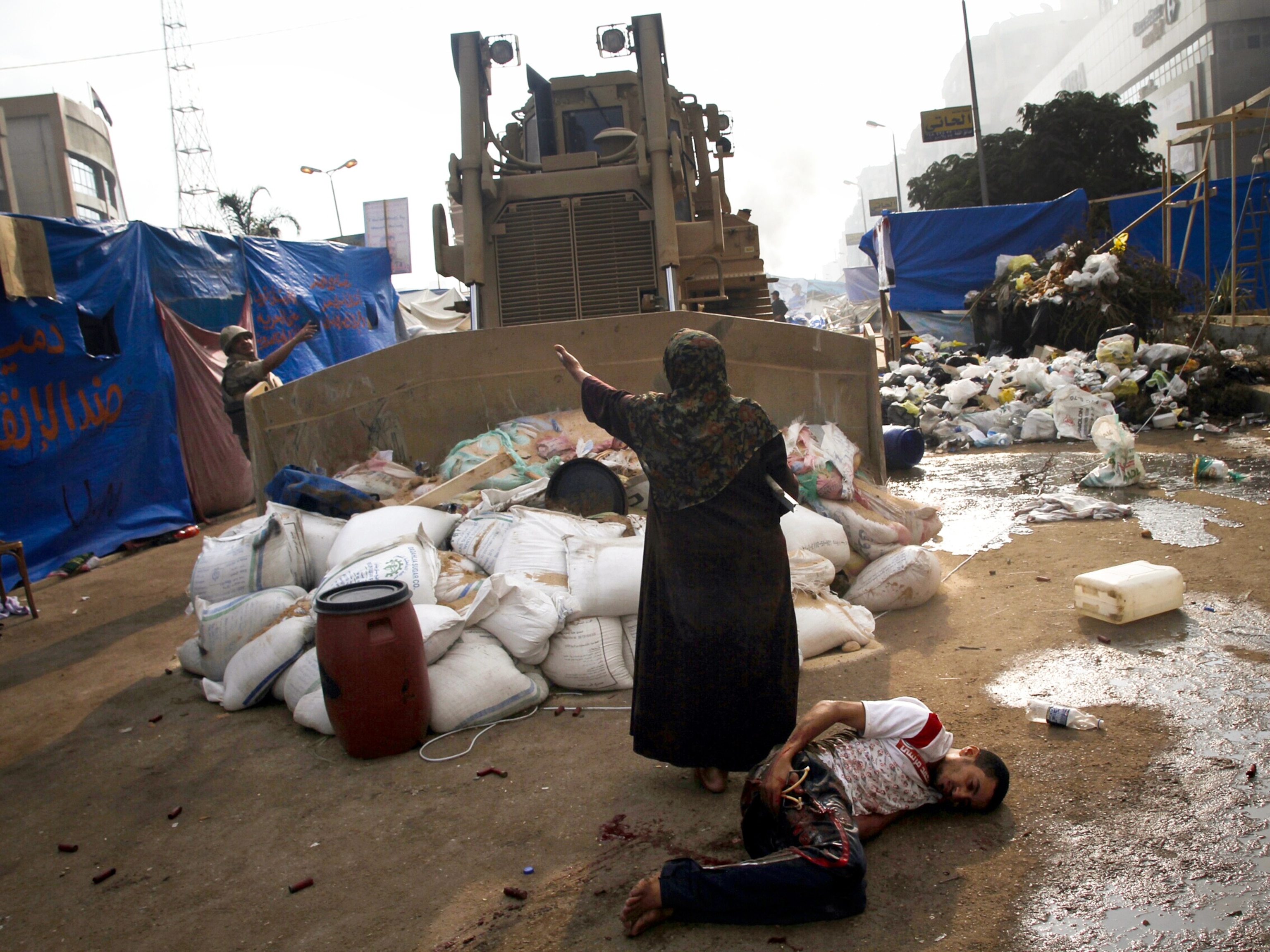 An Egyptian woman stands before a bulldozer.