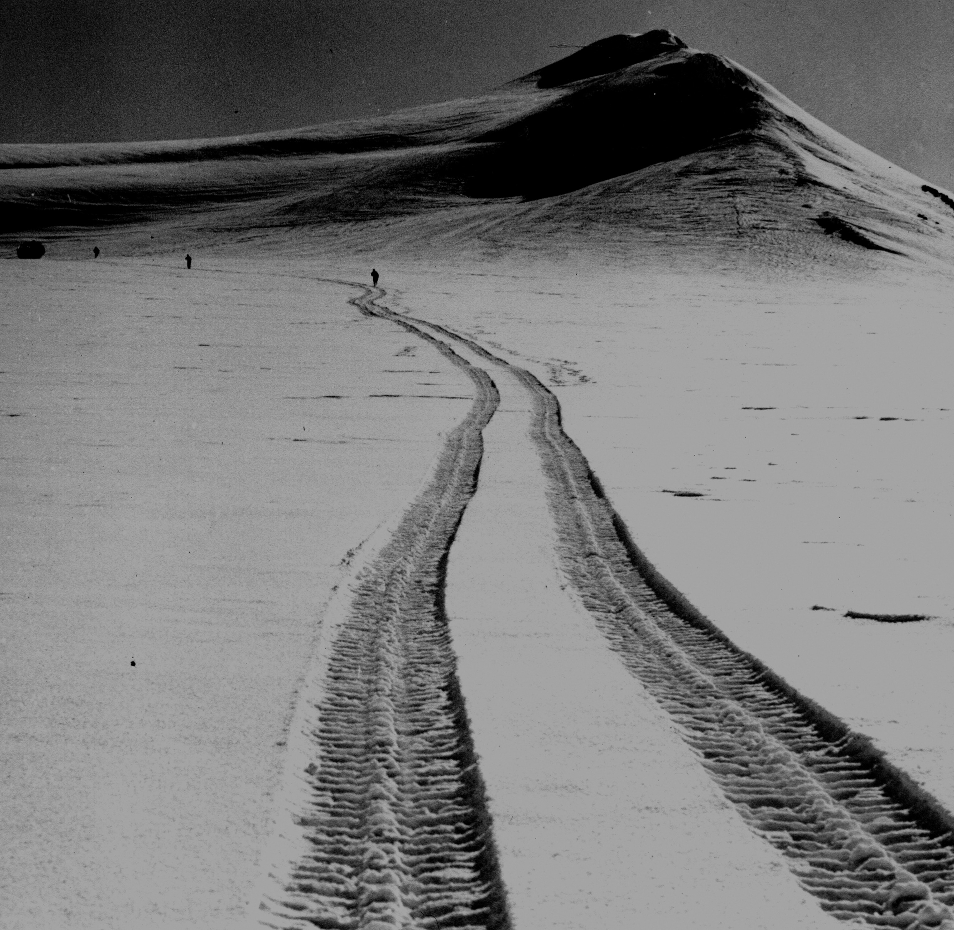 Tire tracks in the snow leading up to a glacier.