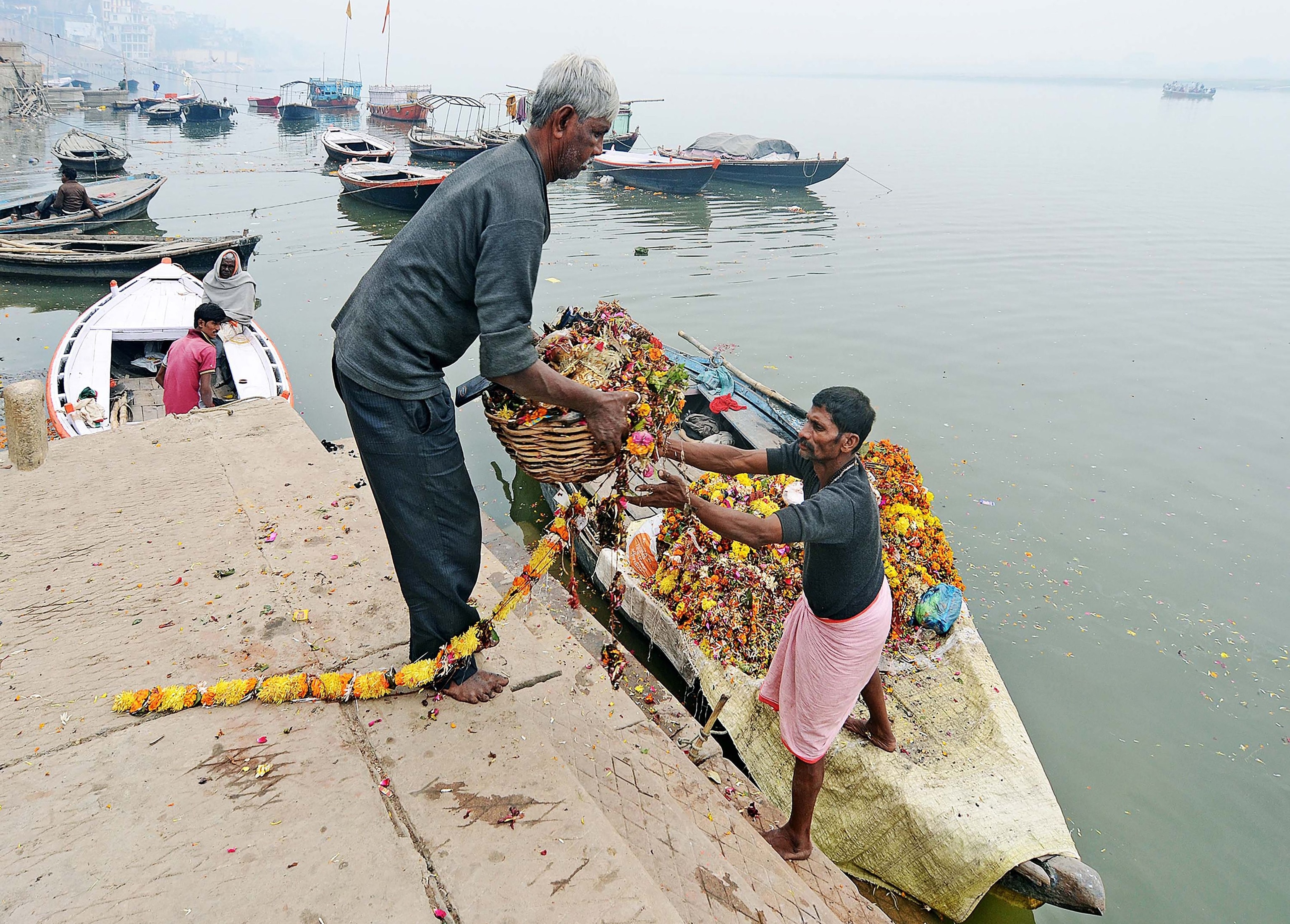 Two men clean offerings from the Ganges