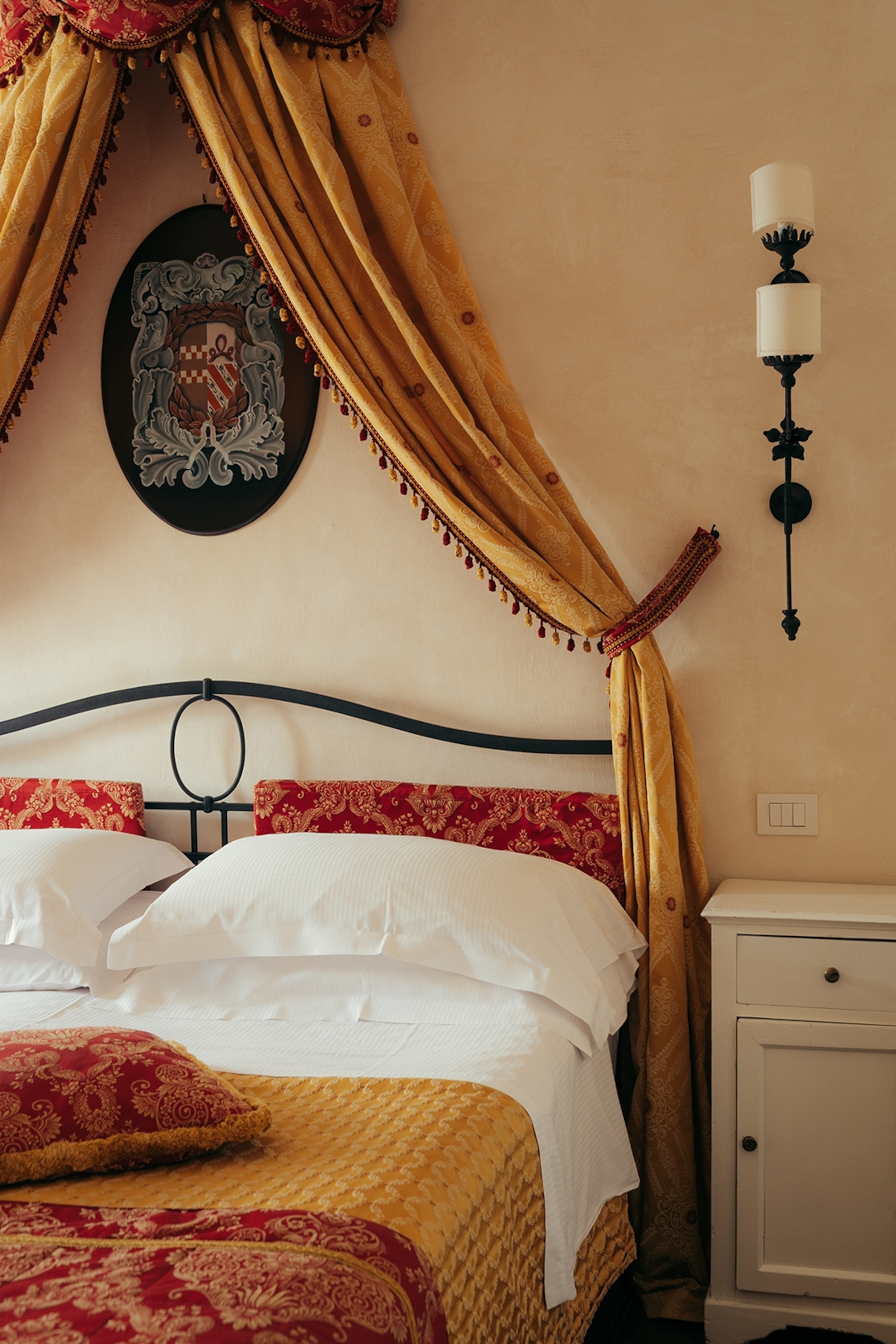 The interiors of an Italian hotel bedroom with drapes around the double bed.
