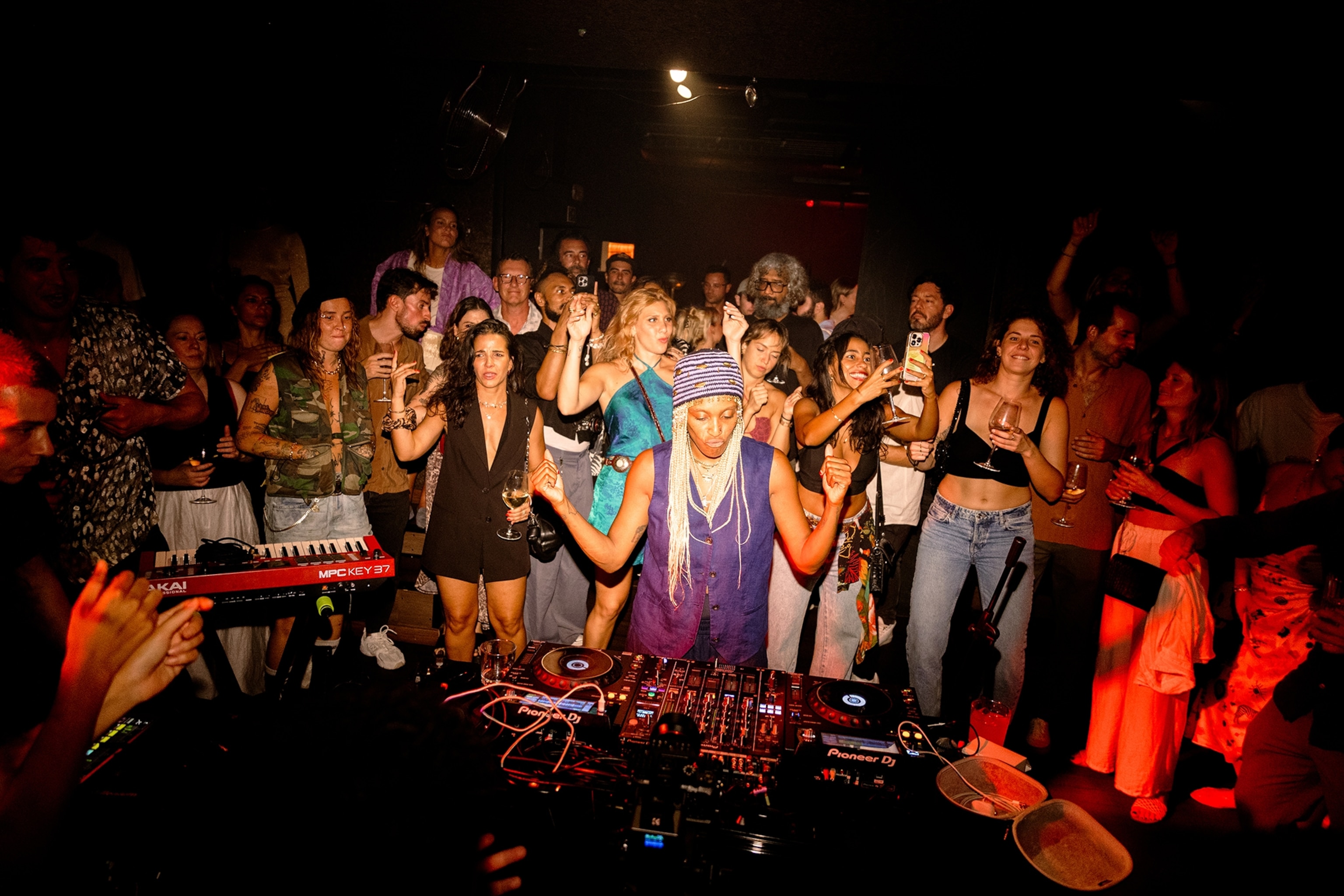 A spotlit DJ in a club surrounded by ecstatic guests.