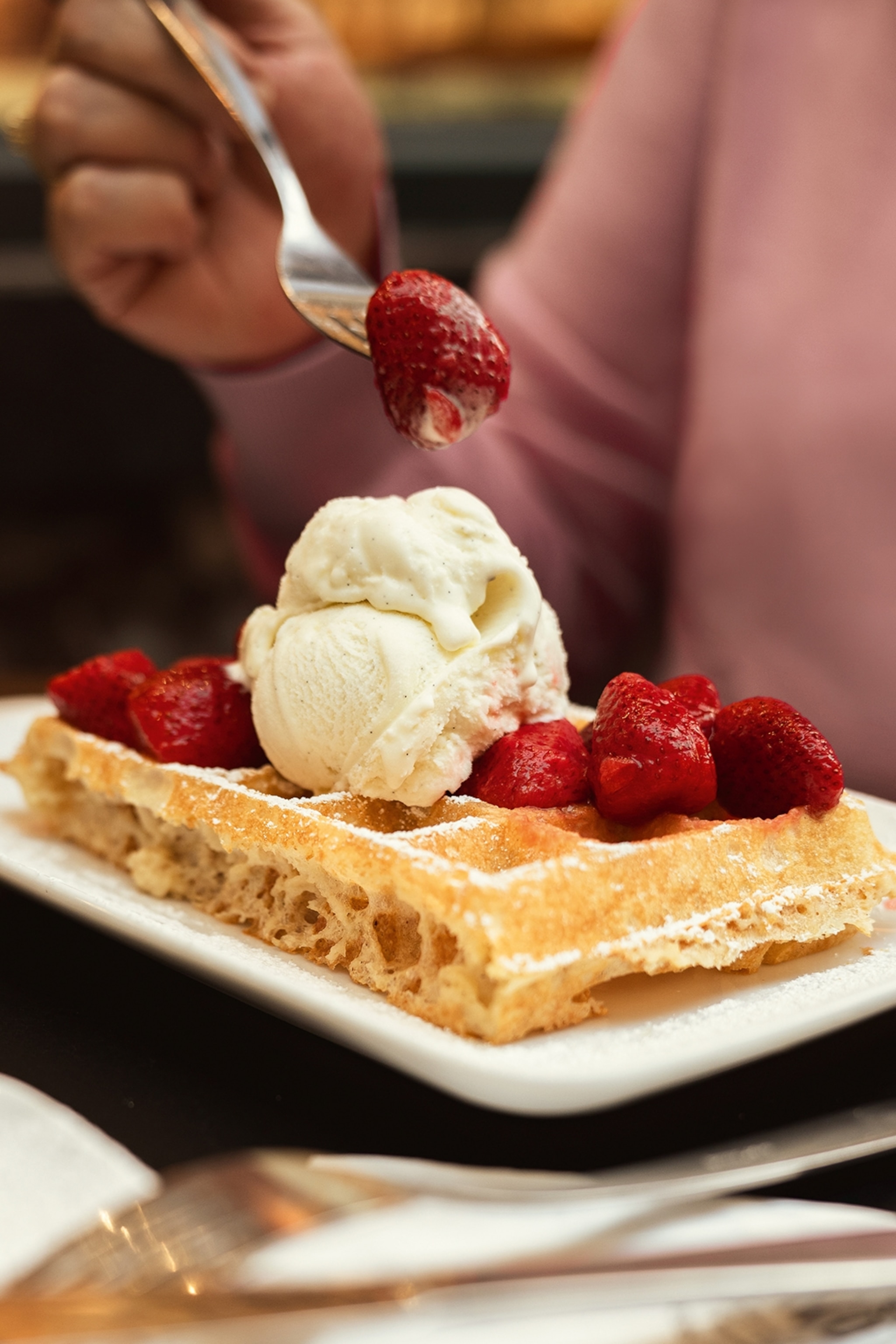 A waffle topped with ice cream and strawberries.
