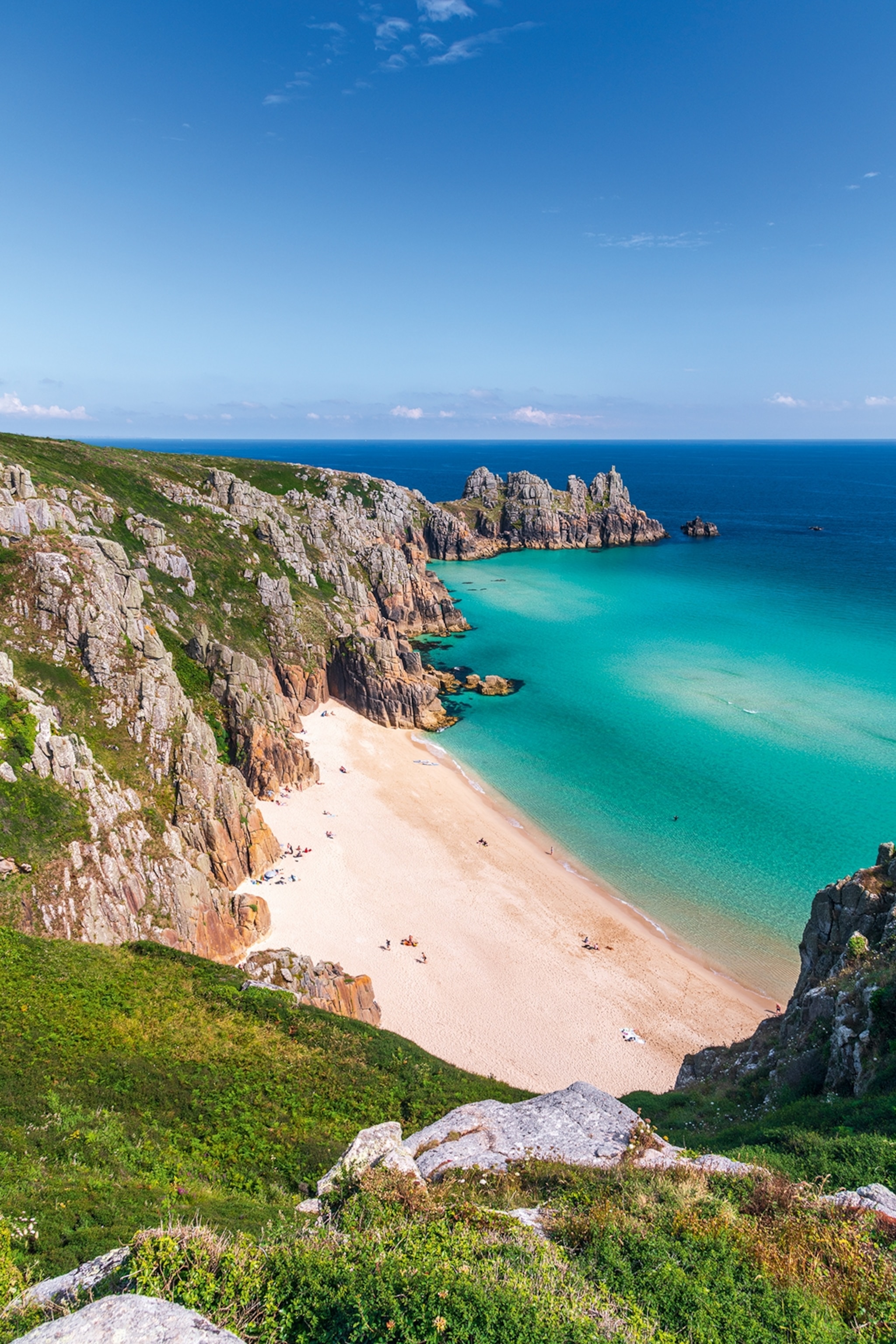 A rugged coast line with clear ocean water and a small beach enclave.