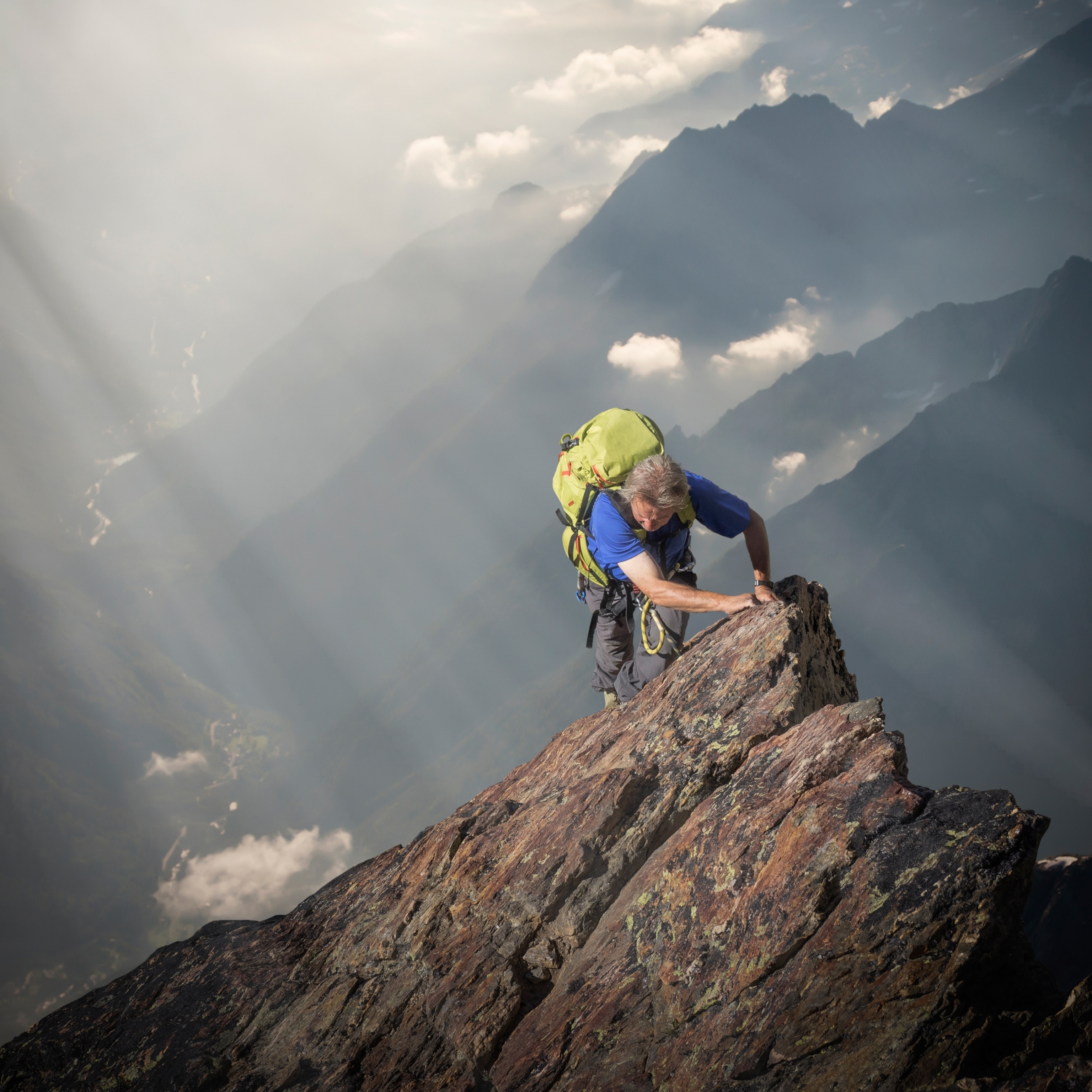 A mountaineer climbing over a rocky ledge on a mountain in the Swiss Alps