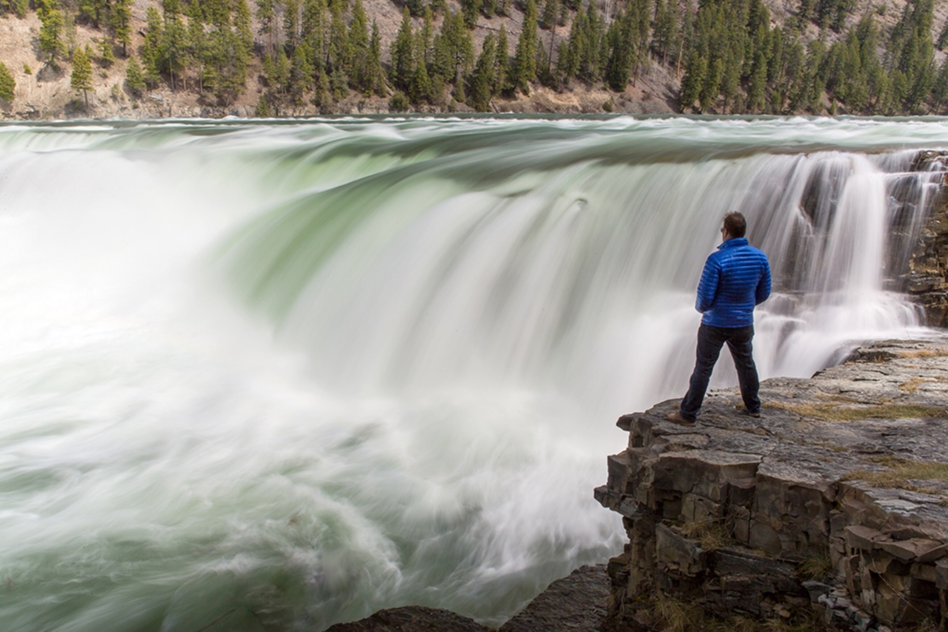 a man standing near Kootenai Falls