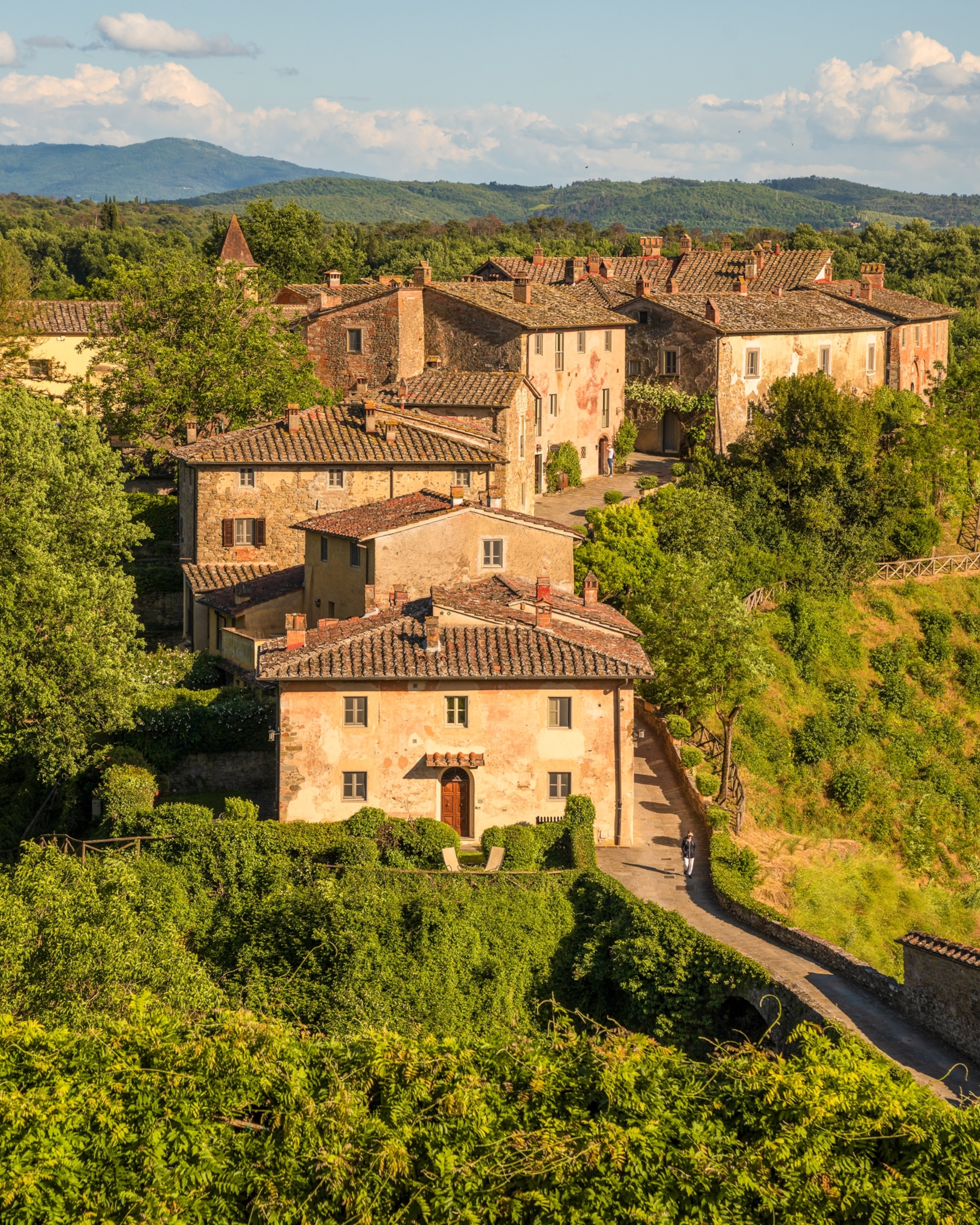 Arial view of multiple stone buildings set into a hillside in Tuscany.