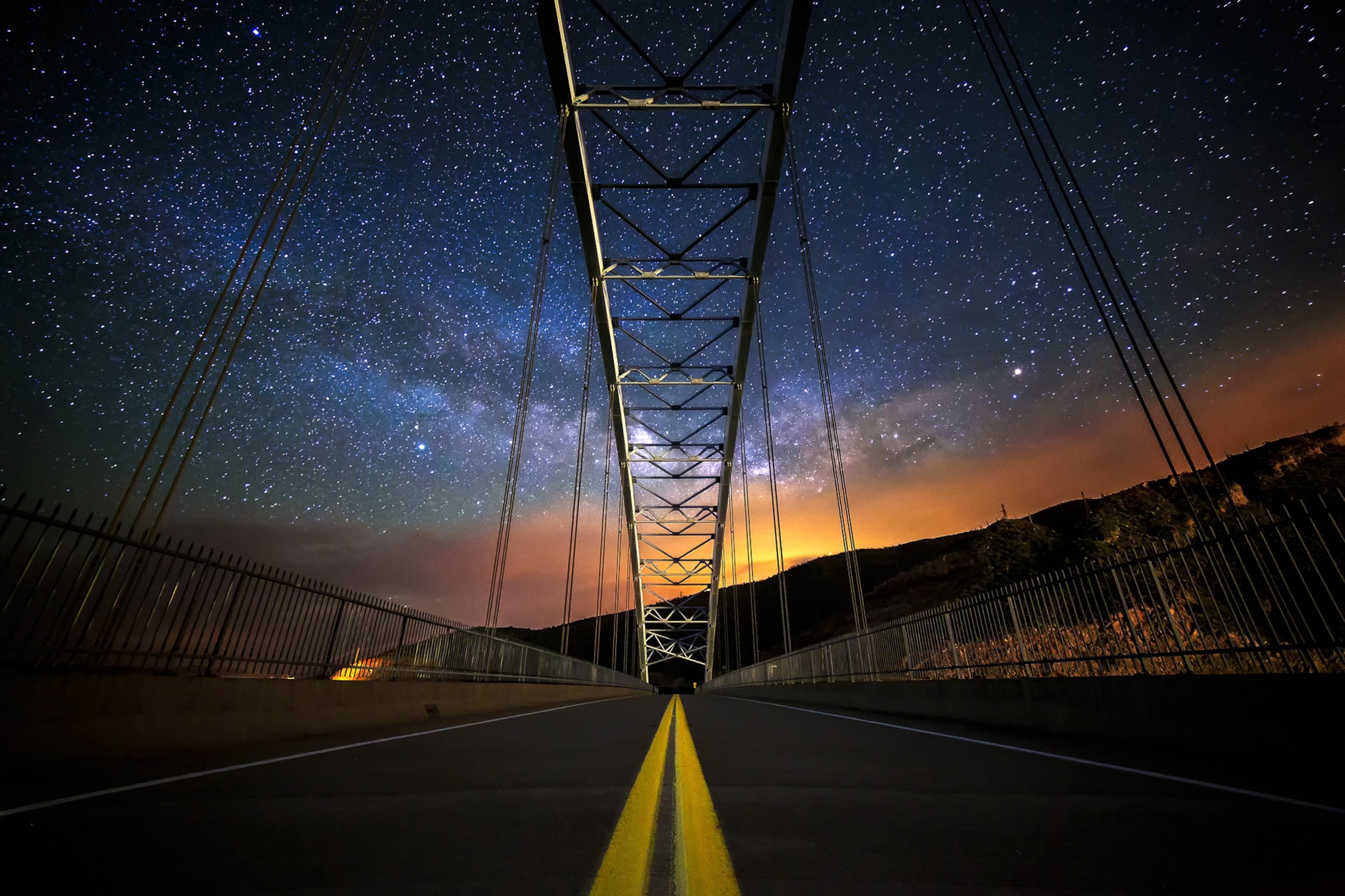 The World at Night - A picture of a bridge underneath a star-covered sky.