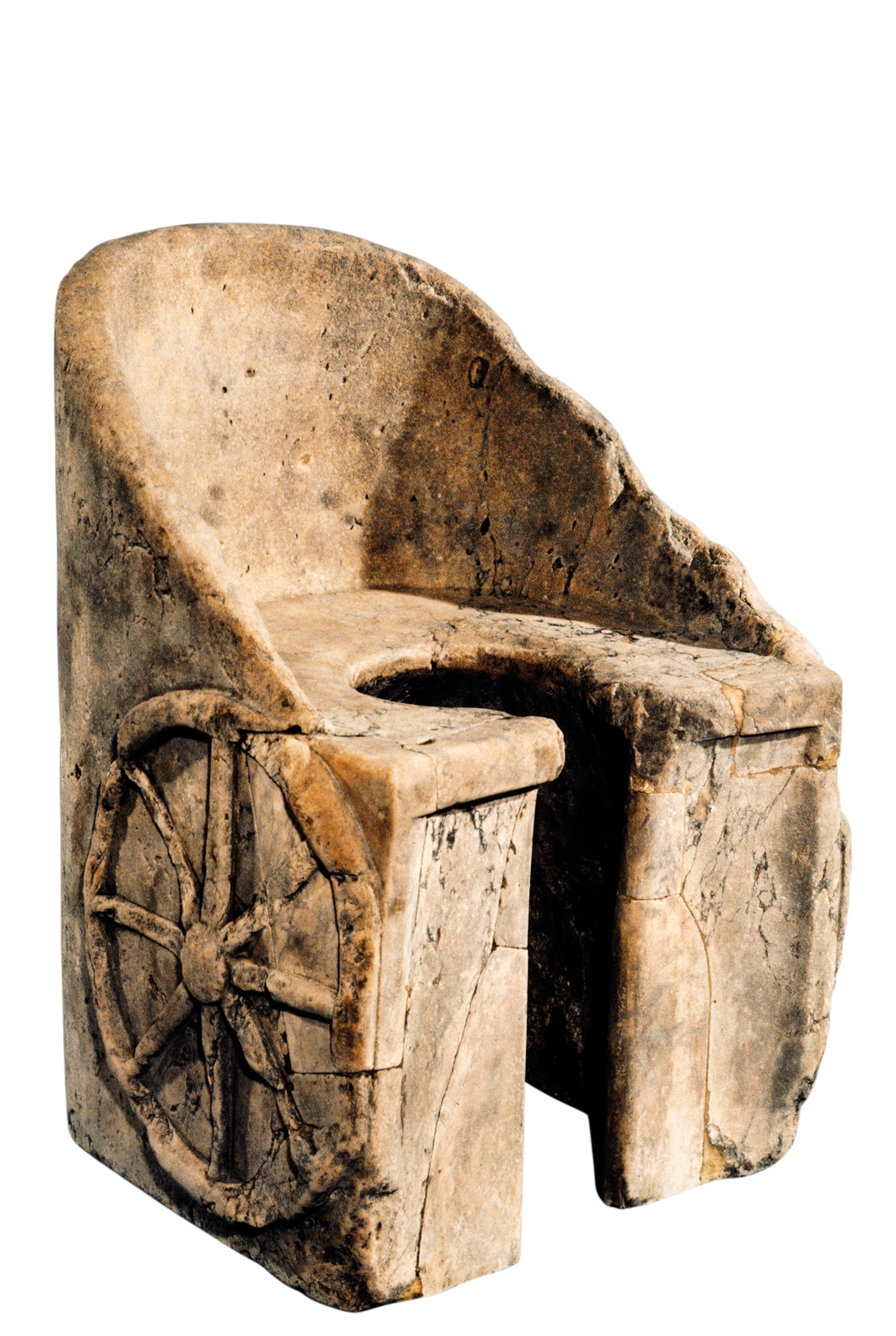 A stone chair with a whole in the seat and wheels carved into the sides