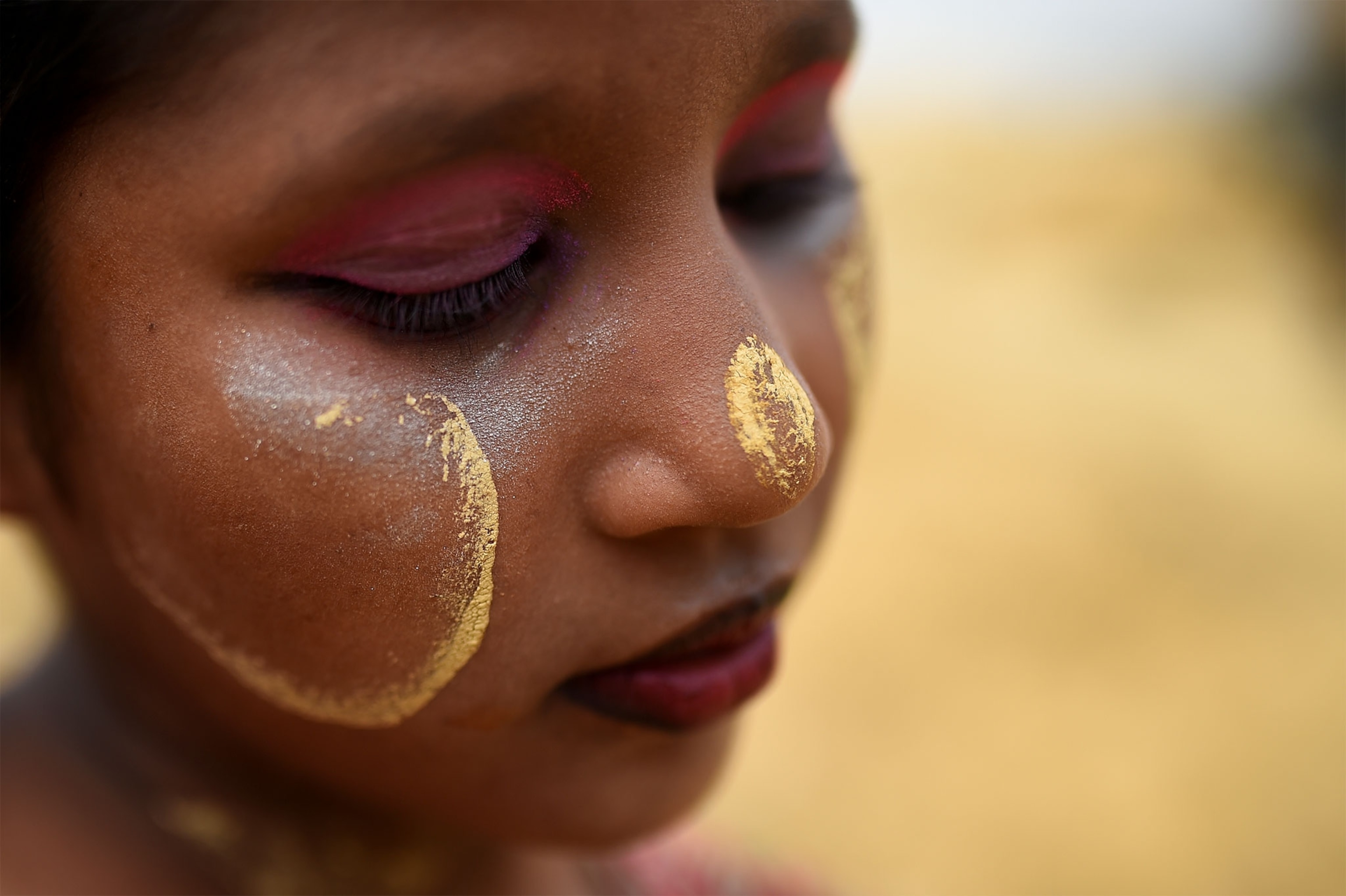 a Rohingya girl wearing paint on her face to protect her from the sun