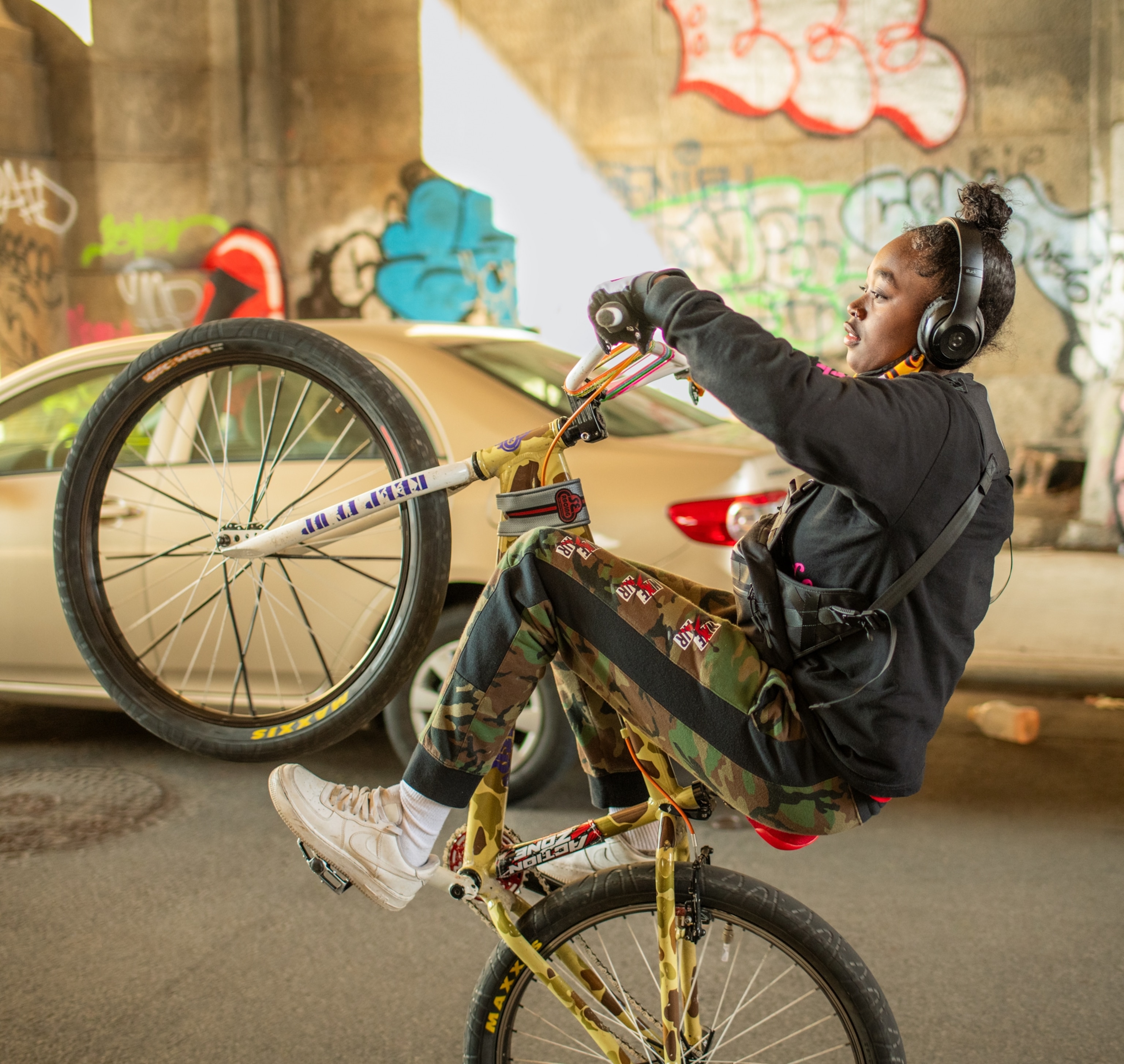 Young woman popping a wheelie under an archway of the Manhattan Bridge.