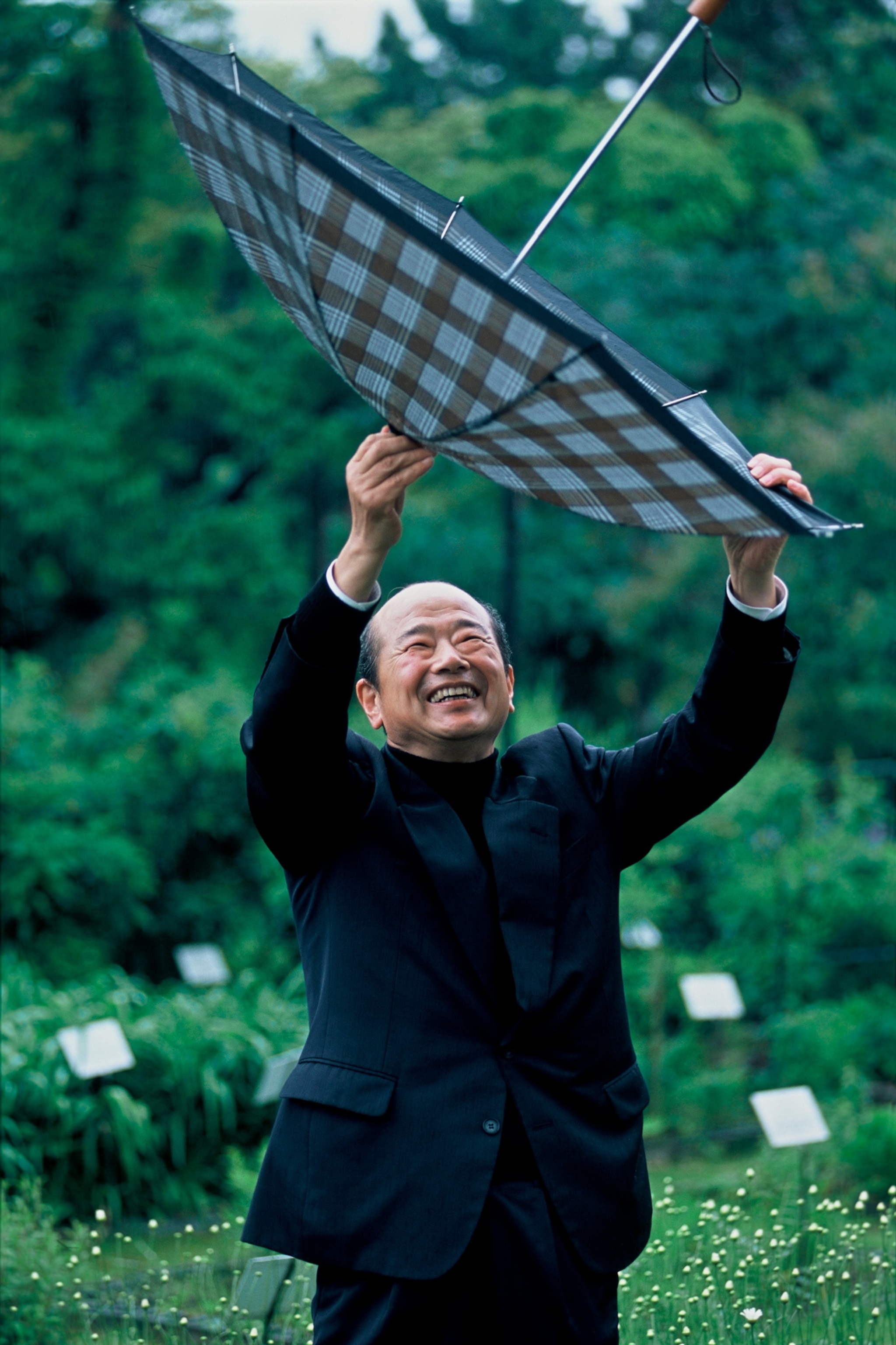 Murase collecting rainwater in an umbrella