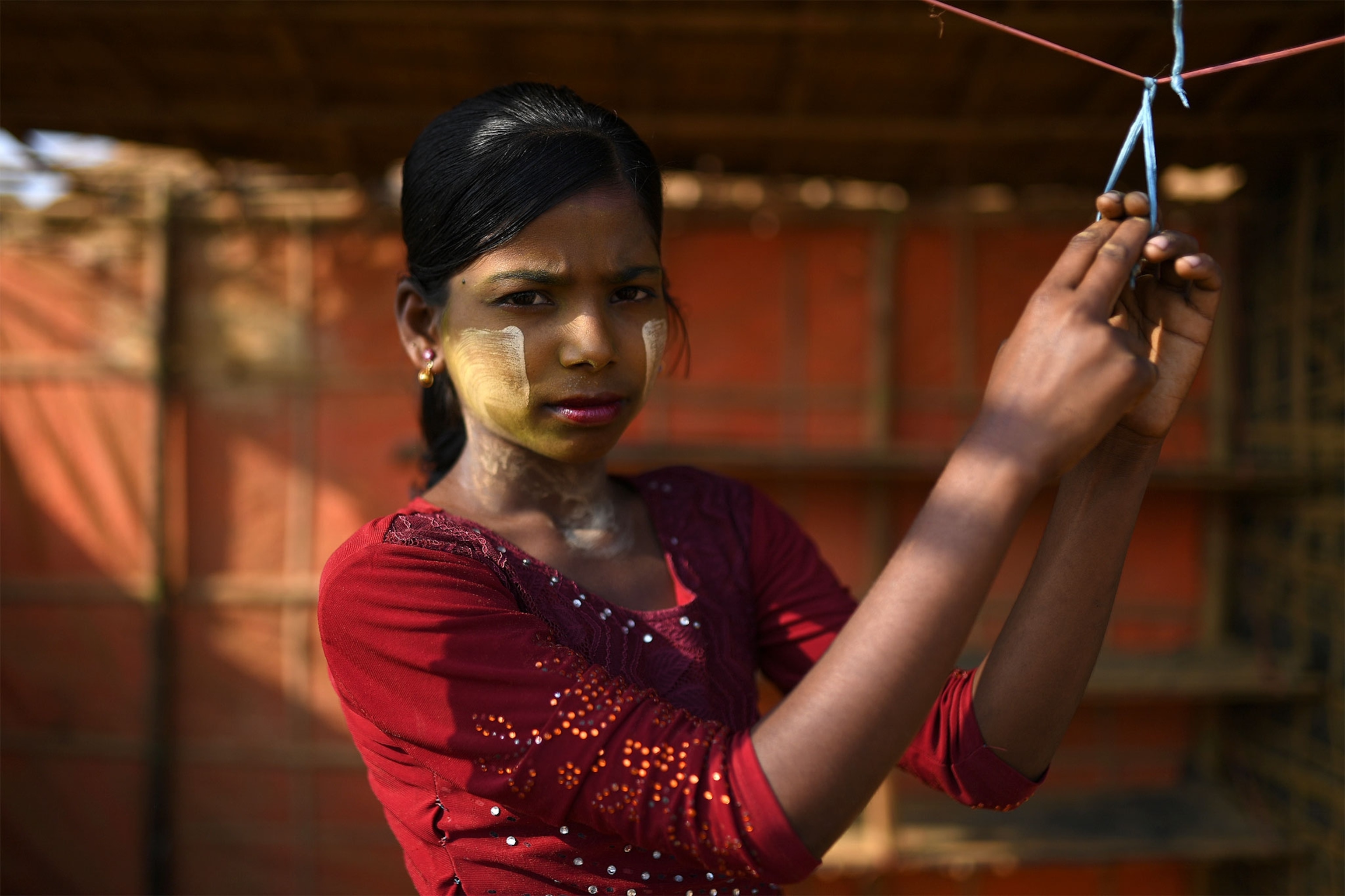 a Rohingya girl wearing paint on her face to protect her from the sun