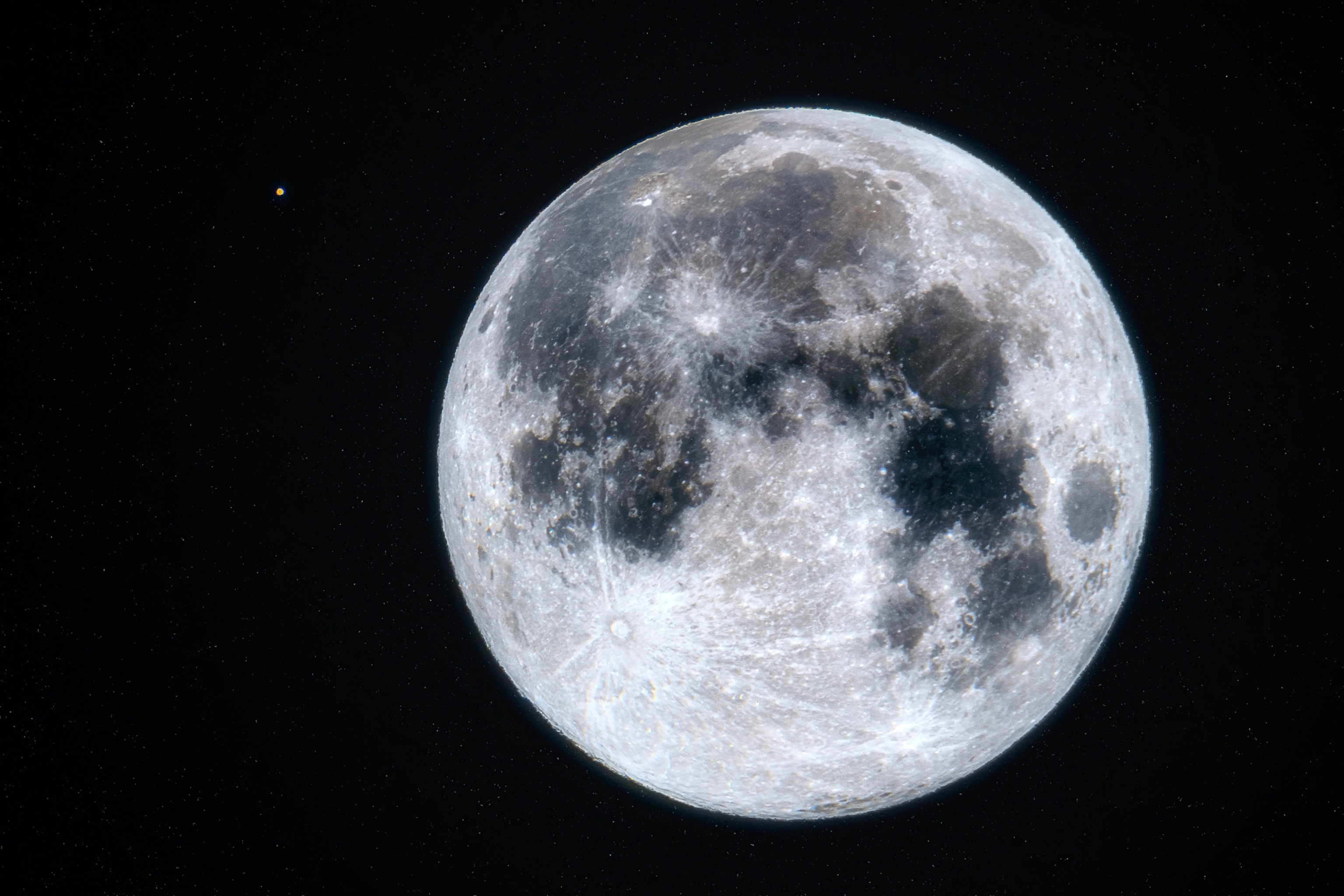 A close-up view of the full moon shows its craters and surface features in detail, with a small bright planet Mars visible against the dark background of space.