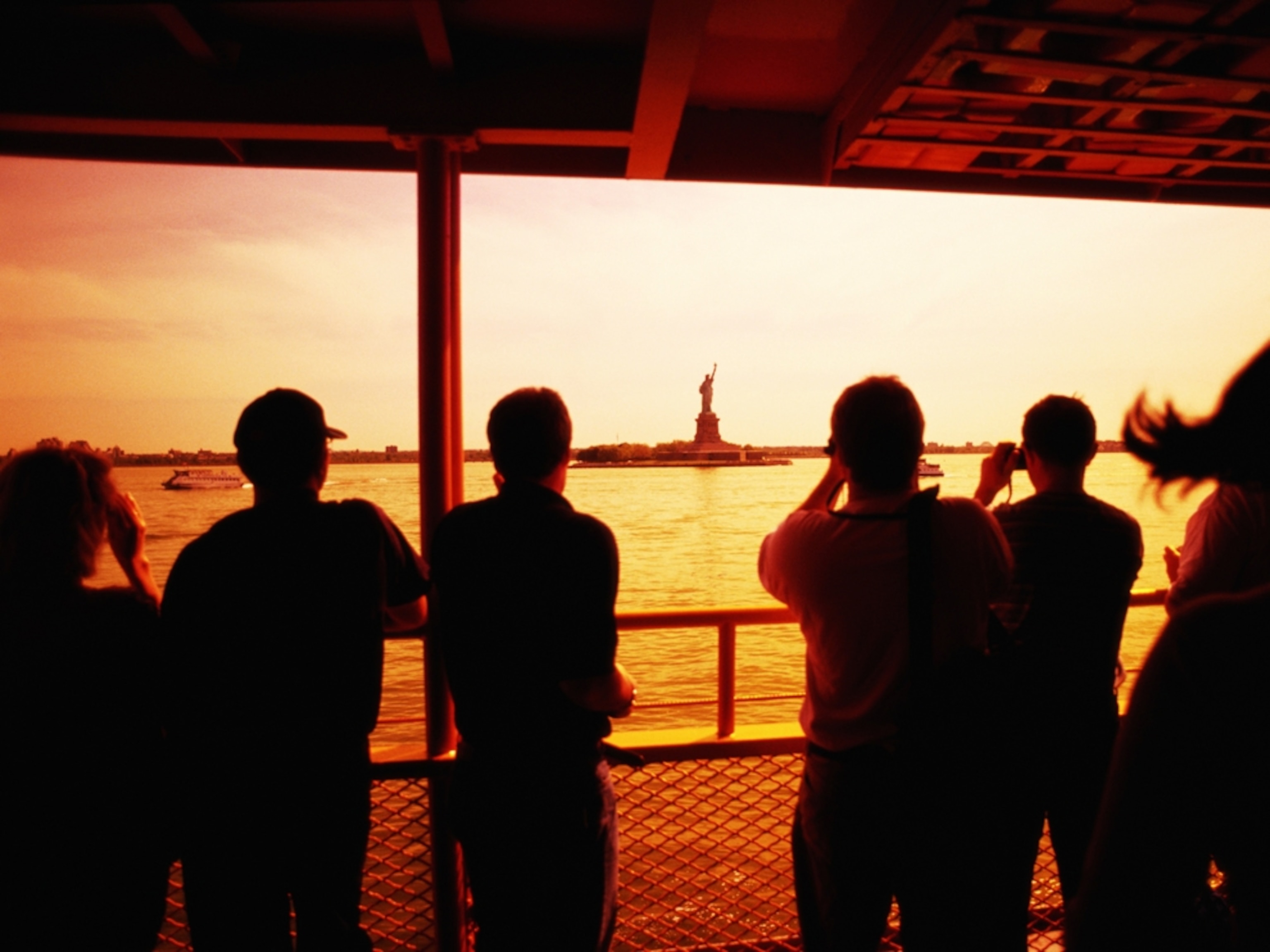 tourists viewing Statue of Liberty from boat at dusk