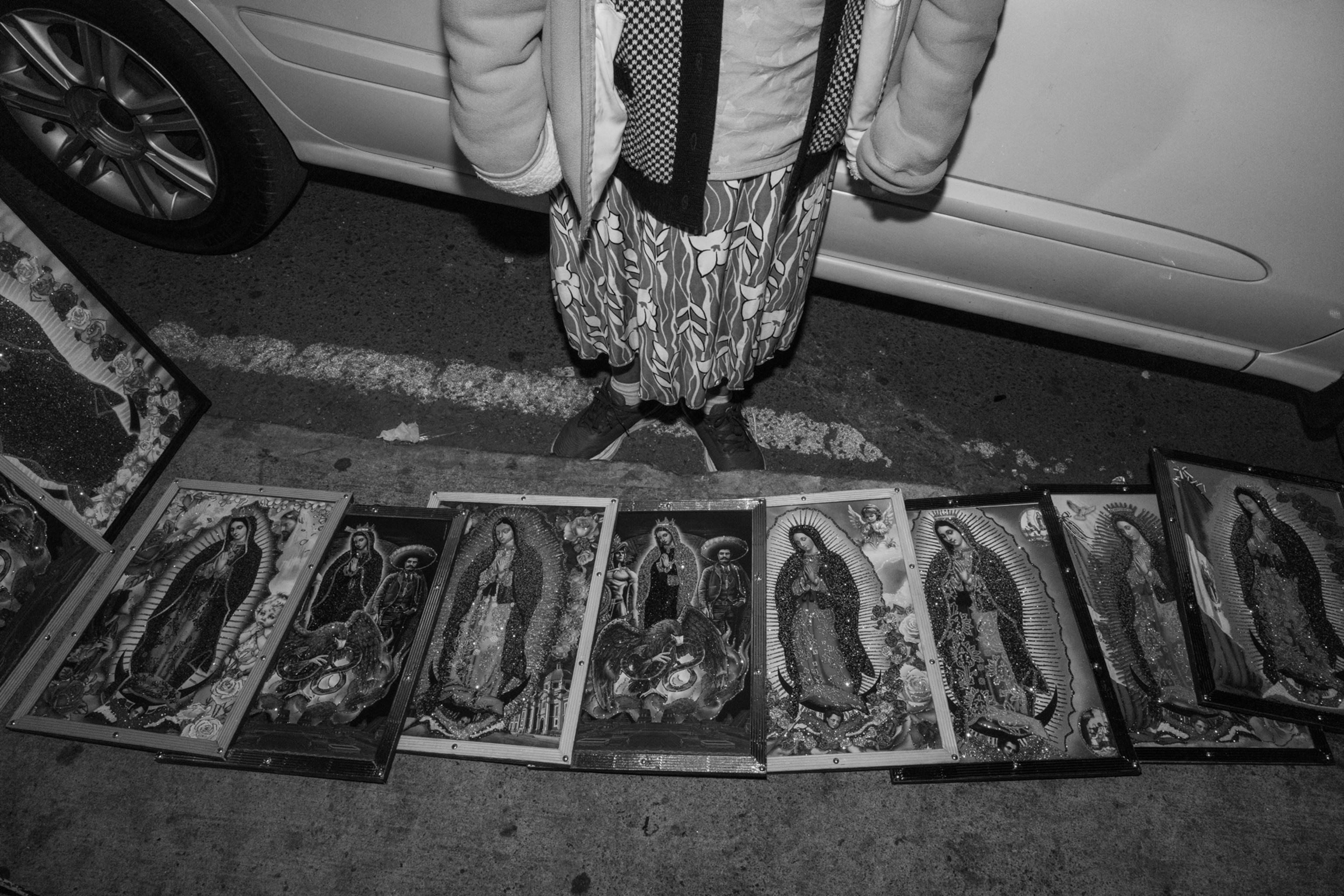 A persons feet is seen amongst many paintings of a woman praying