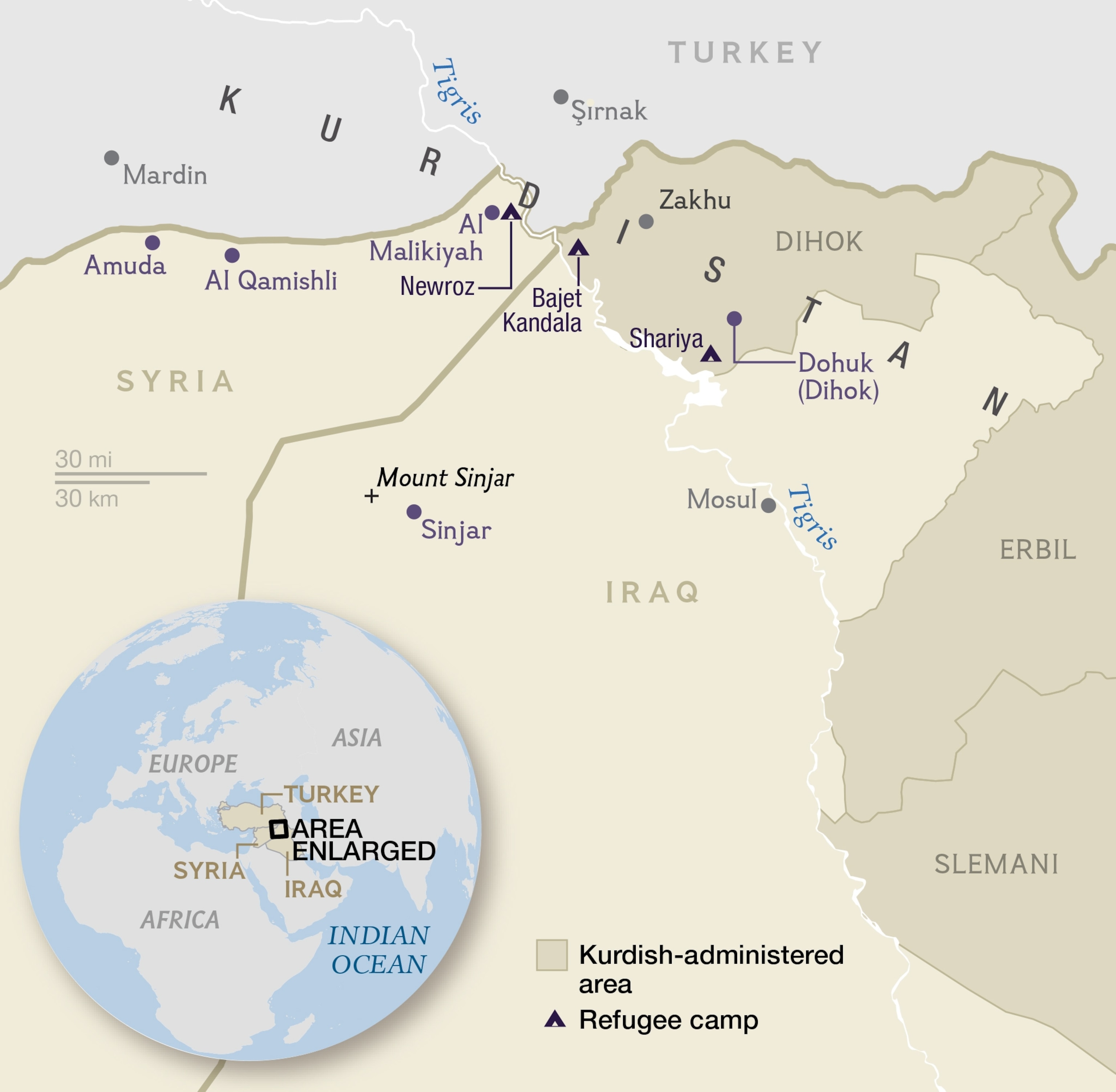 a refugee wrapping himself with a blanket as he stands on a muddy path during wintry weather.