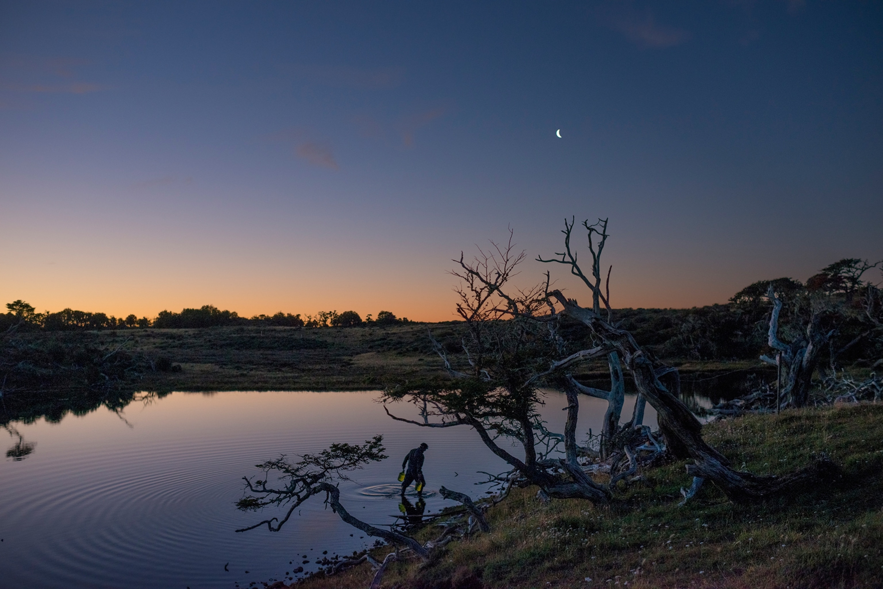 a man collecting water from a lake at night