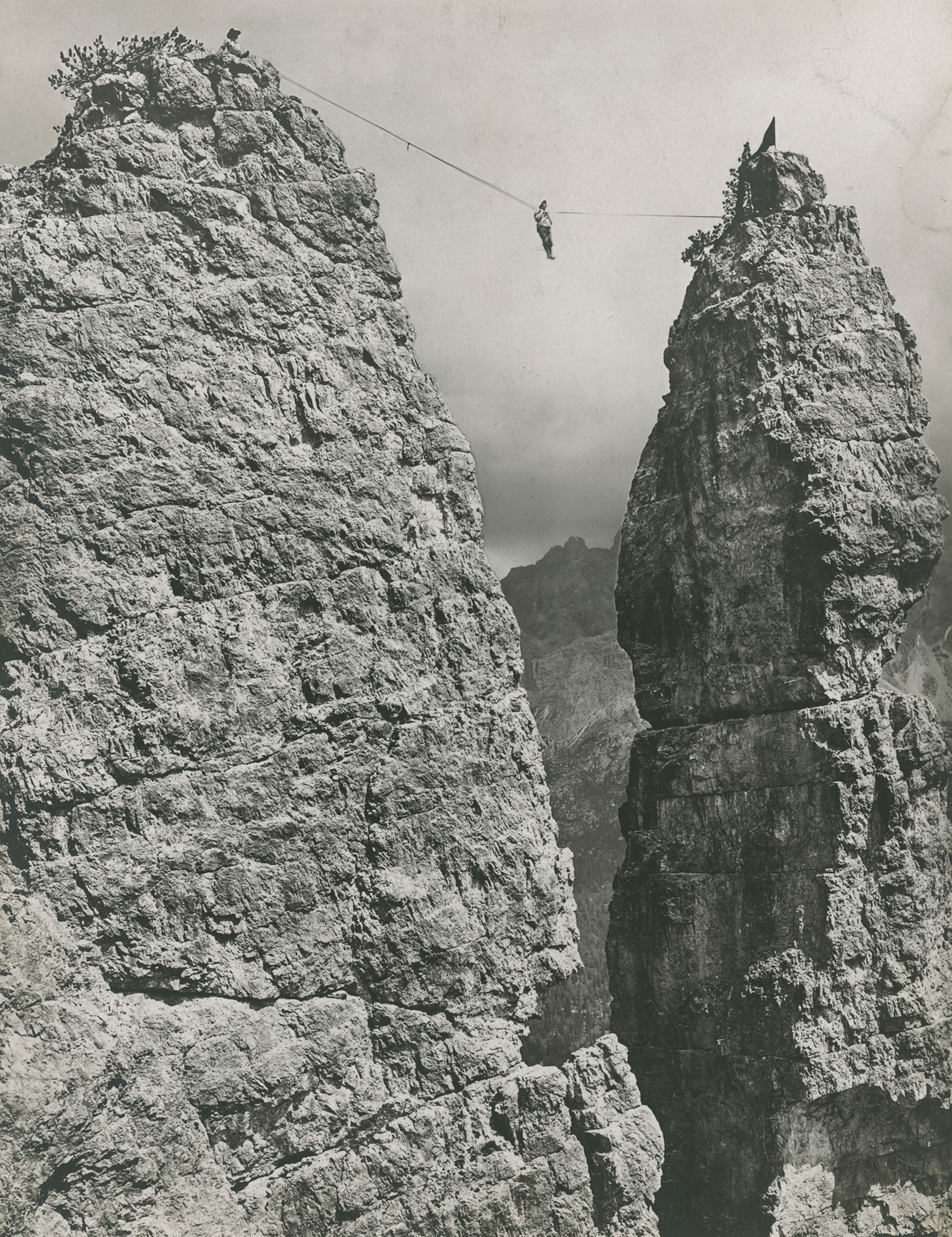 a rock climber walking on a tightrope between peaks