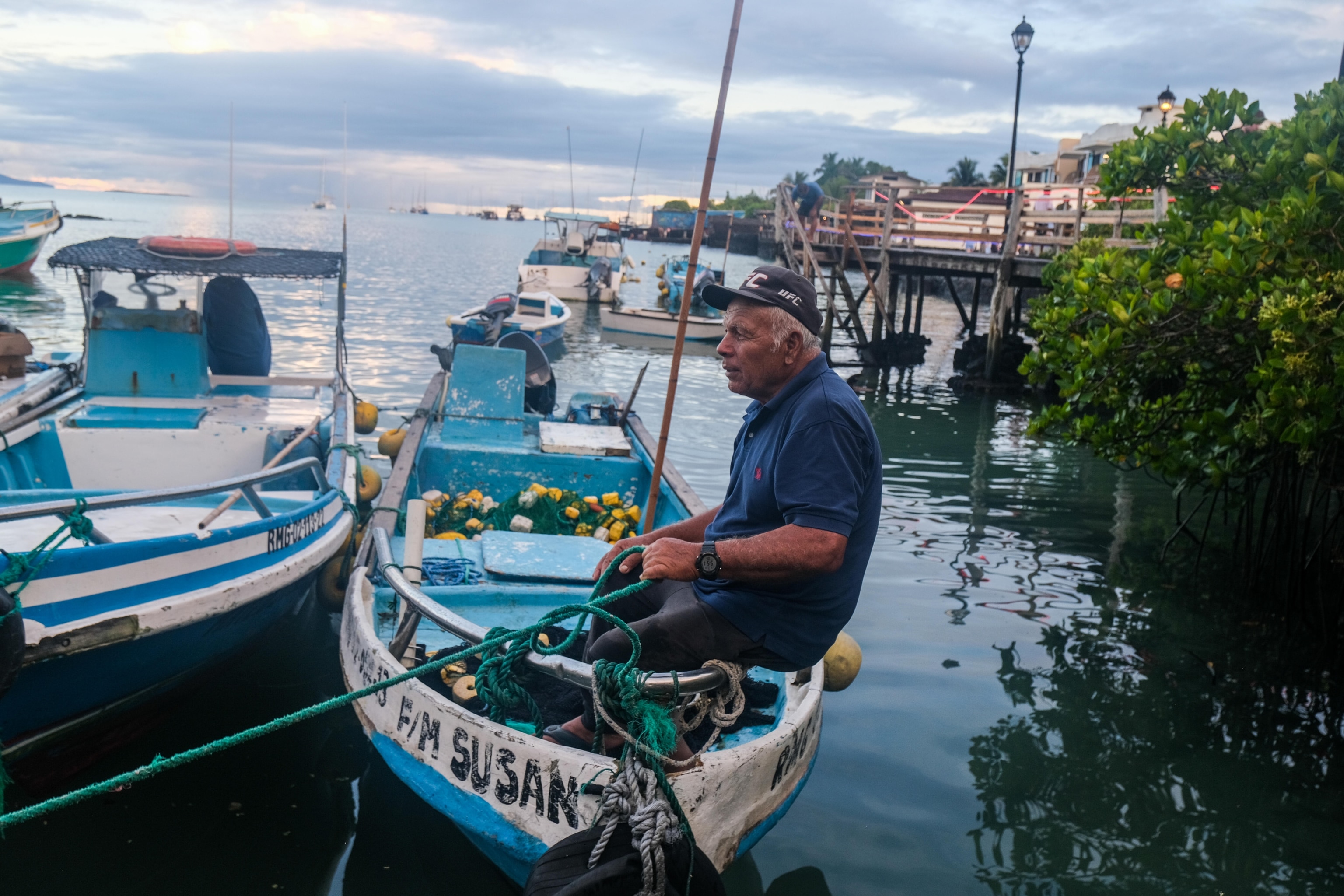 The National Geographic Society, in partnership with Lindblad Expeditions, organized a series of National Geographic Photo Camps in the Galápagos. These camps aim to provide young people across the islands with an engaging introduction to photography and storytelling, empowering them to explore and reflect on what it means to be "Galapagueño." A fisherman with his boat during sunset at Santa Cruz port. Photographer: Escarleth Tubón. Santa Cruz, Galápagos, Ecuador, February 2025.