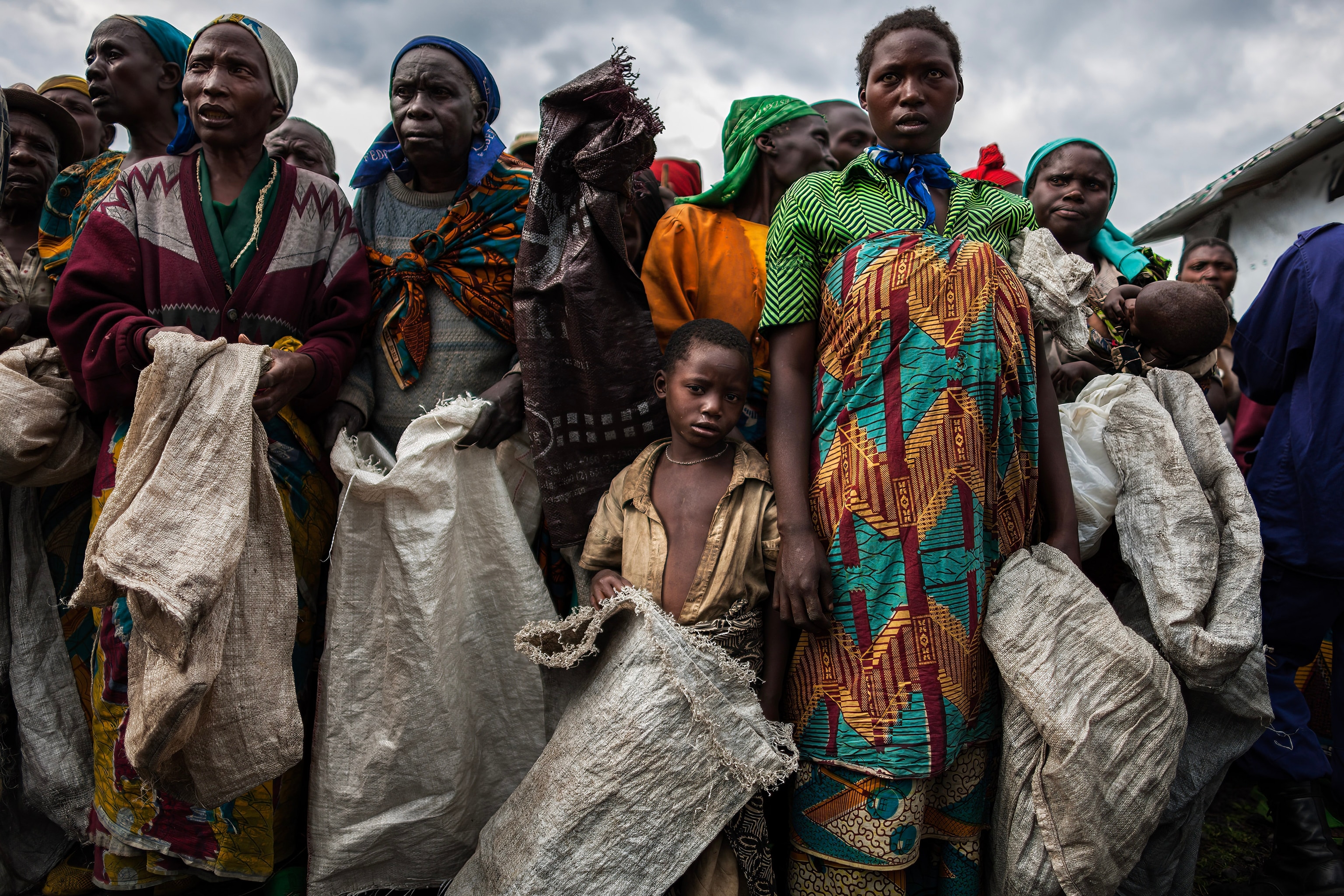 A group of people looking distressed and into the camera, holding bags used for charcoal