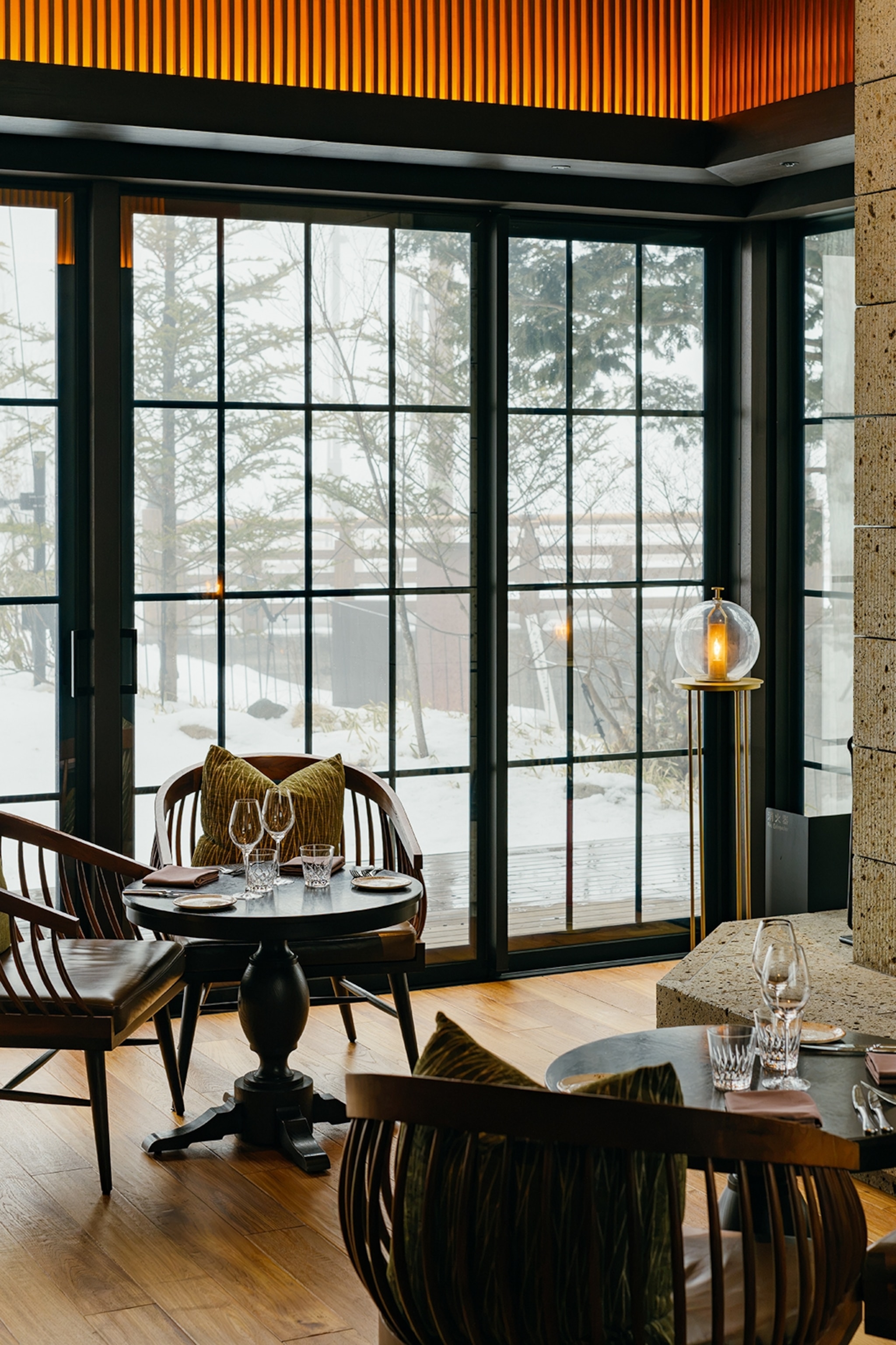 The sleek interiors of a bar with floor-length windows revealing an icy forest.