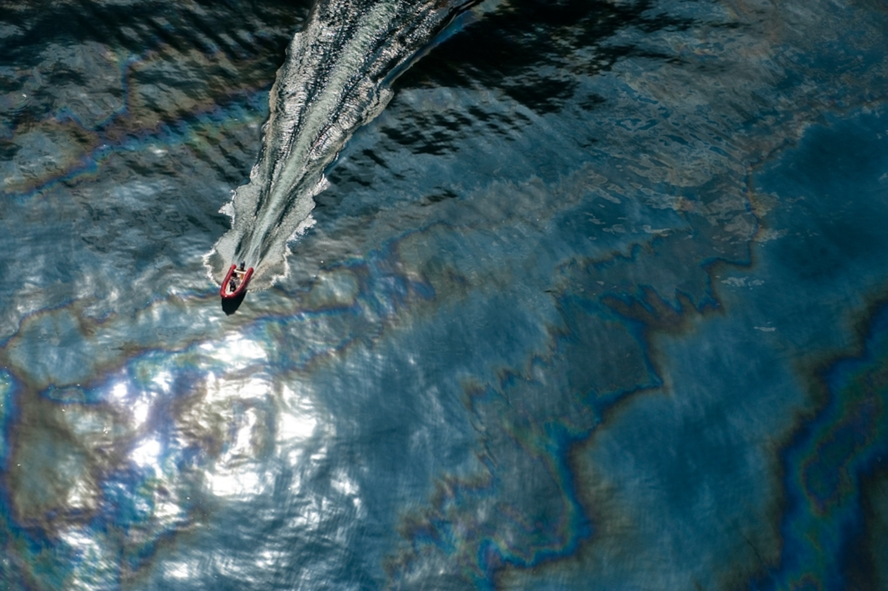 A boat cuts through surface oil near the Deepwater Horizon blowout.