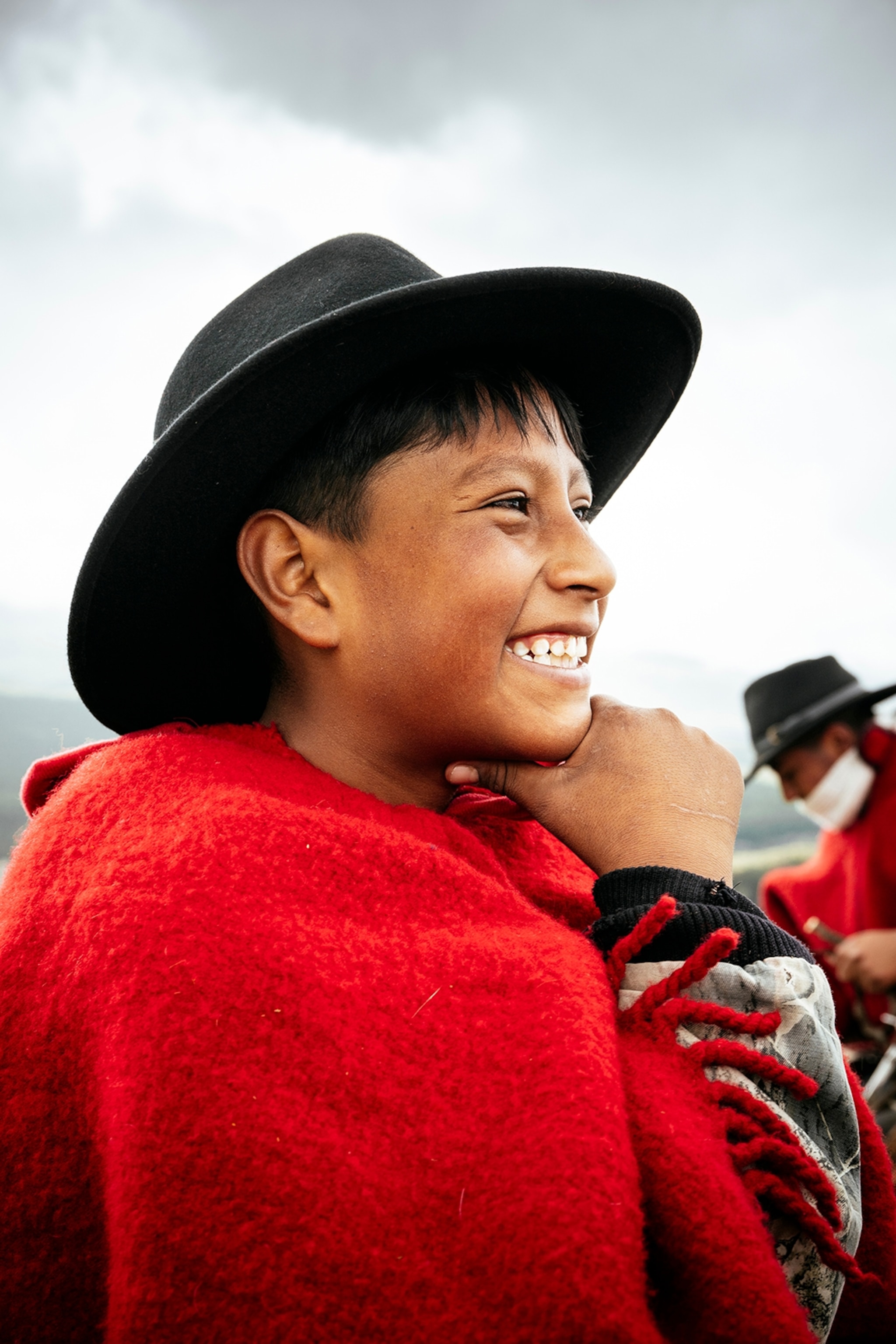 A smiling boy in Ecuador wearing a cowboy poncho and hat.