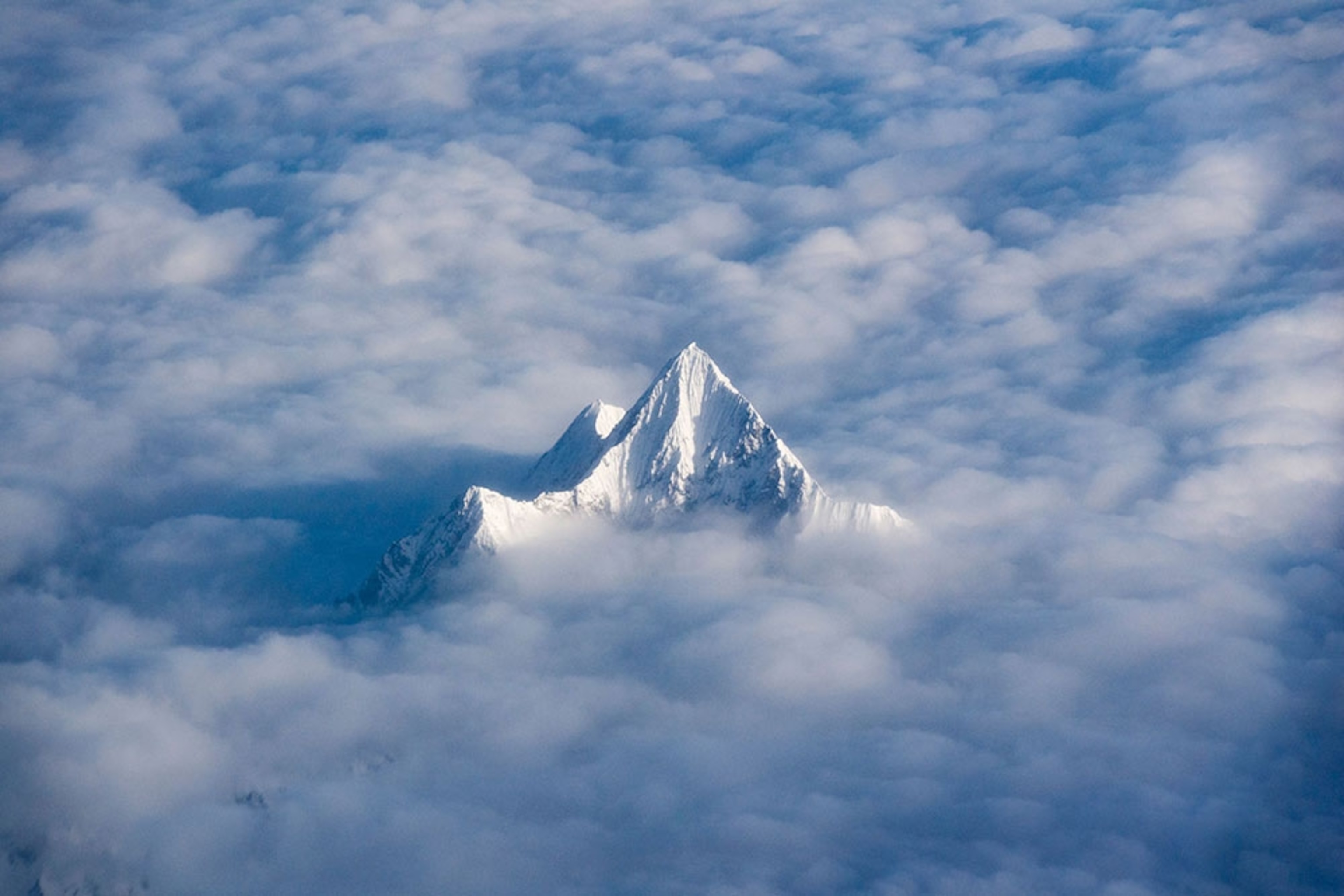a snow- and ice-covered Himalaya peak rises above the clouds.