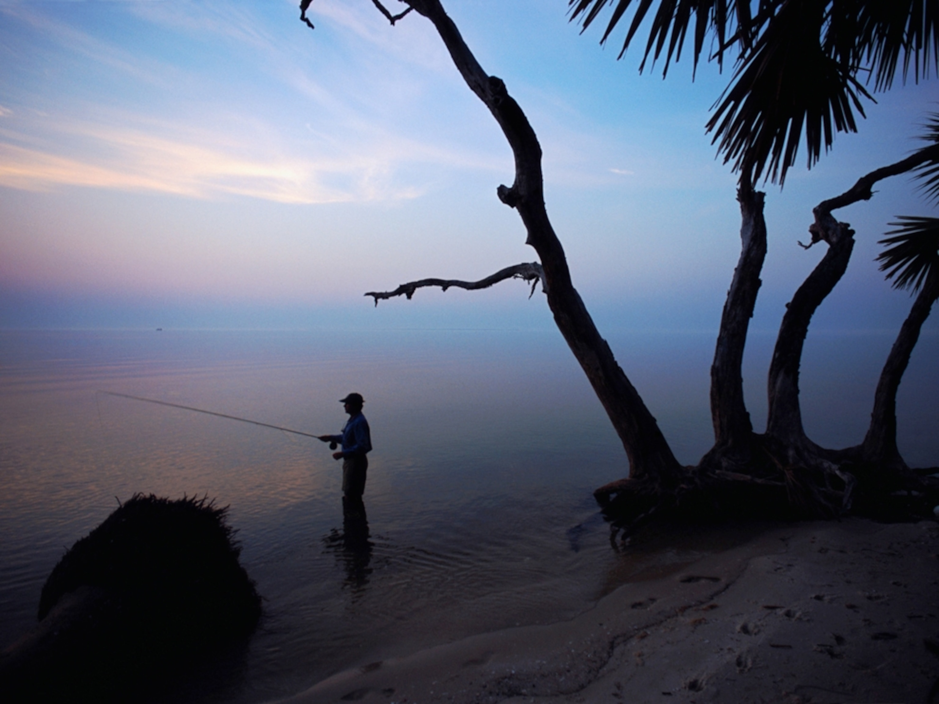 fisherman in shallow water at St. Vincent Island, Florida
