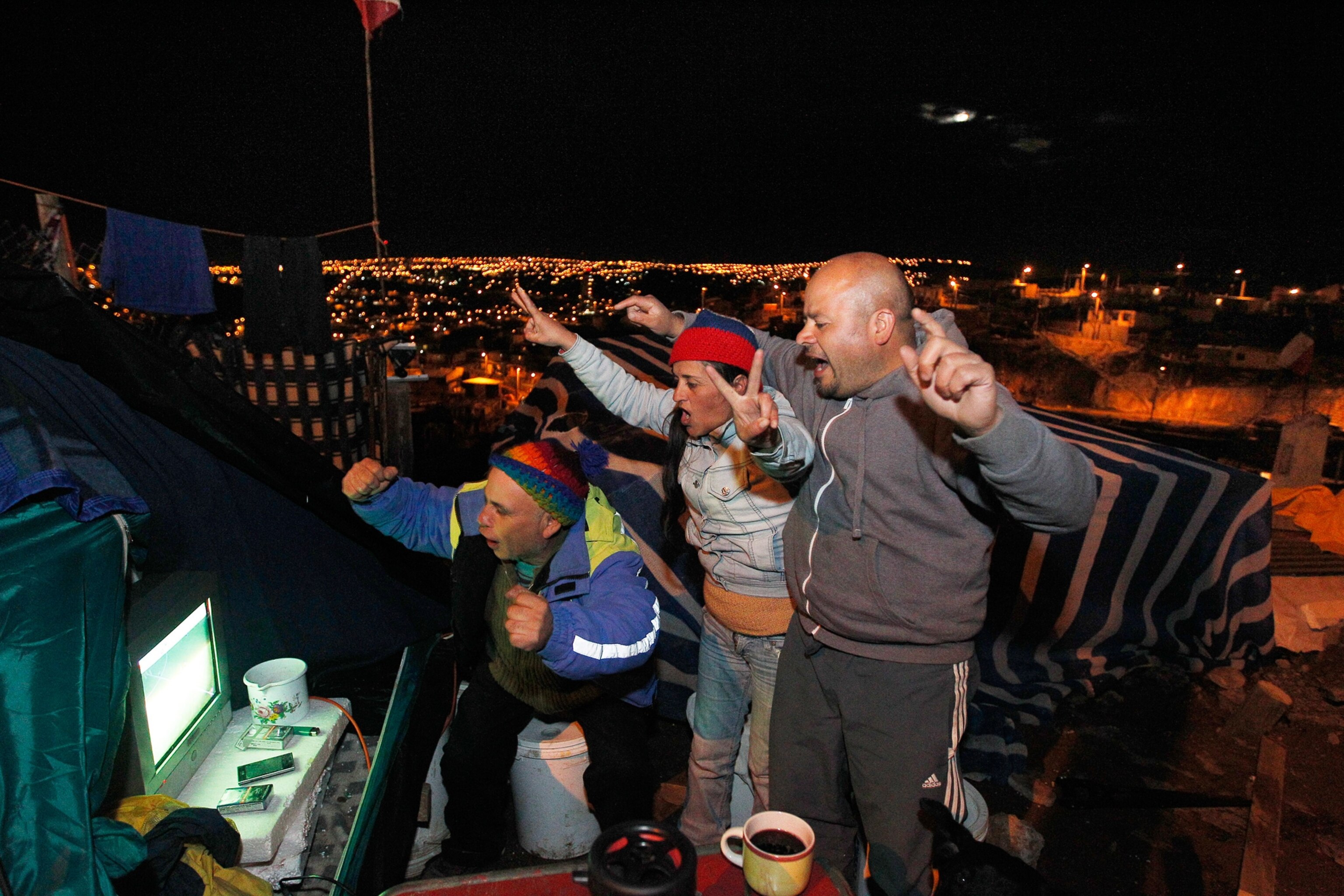 Fans of Chile celebrate the team's victory over Australia in their first 2014 World Cup match, as they watch the screening on a television outside their makeshift tent on the hills of Las Canas in Valparaiso city, northwest of Santiago.