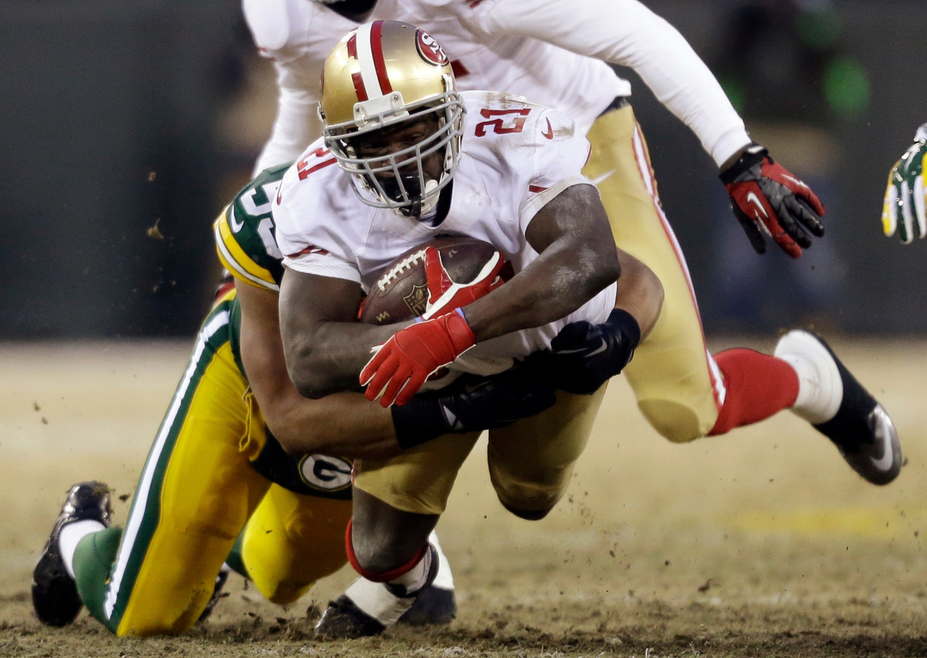 San Francisco 49ers running back Frank Gore (21) gets tackled by Green Bay Packers cornerback Micah Hyde (33) during the first half of an NFL wild-card playoff football game, Sunday, Jan. 5, 2014, in Green Bay, Wis.