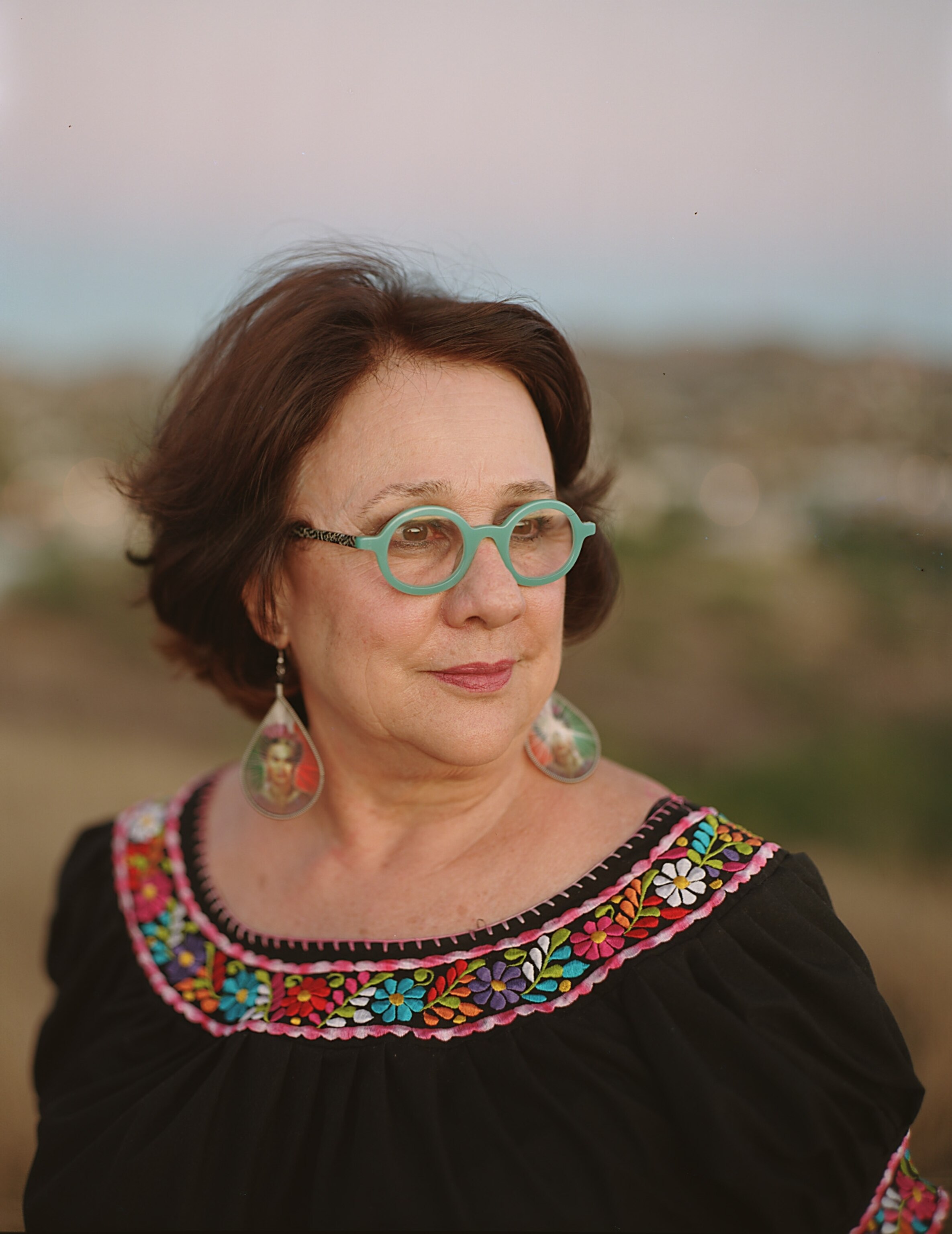 Yolanda Soto, CEO of Borderlands Food Bank, near her home in Nogales, Arizona. The border between the U.S. and Mexico can be made out in the background. Photograph by Bryan Schutmaat
