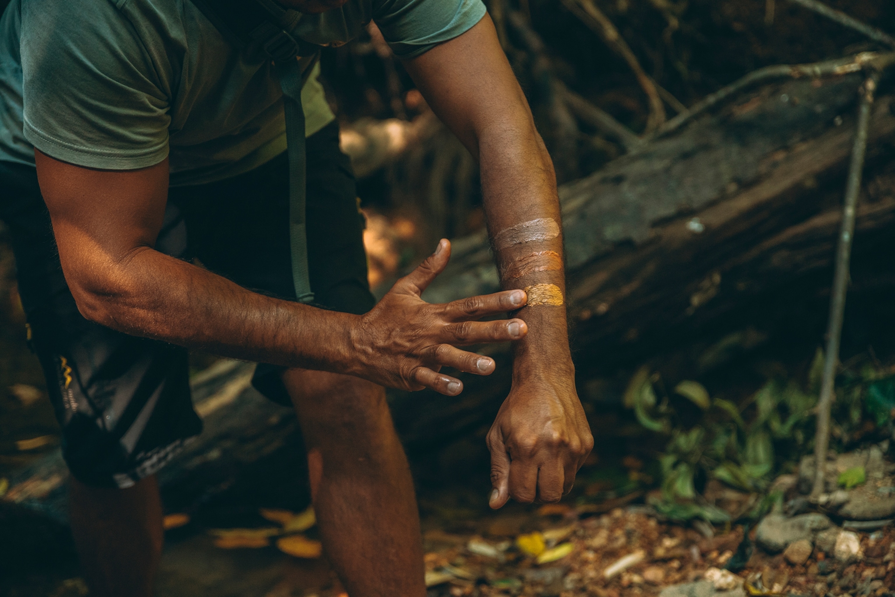 Close up of Indigenous guide painting his arm with three different shades of ochre with his finger