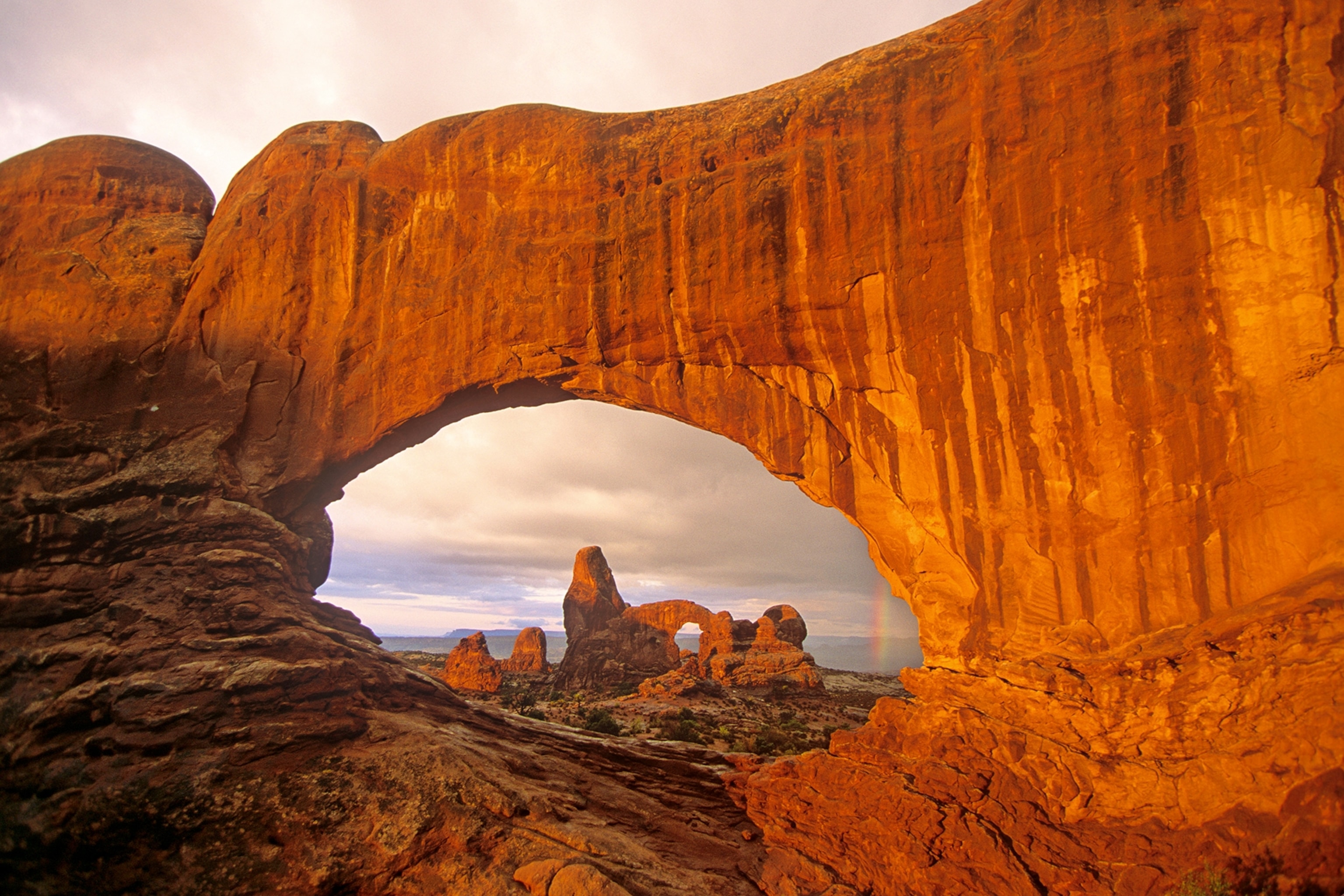 Turret Arch and rainbow, seen through North Window at Arches National Park, Utah