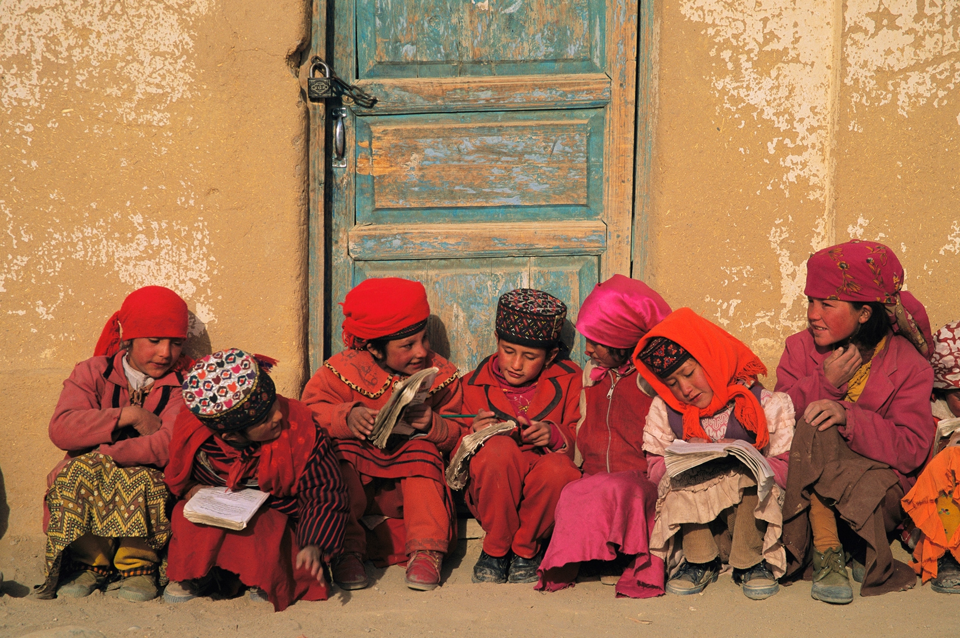 Tajik children review tattered class notes before school.