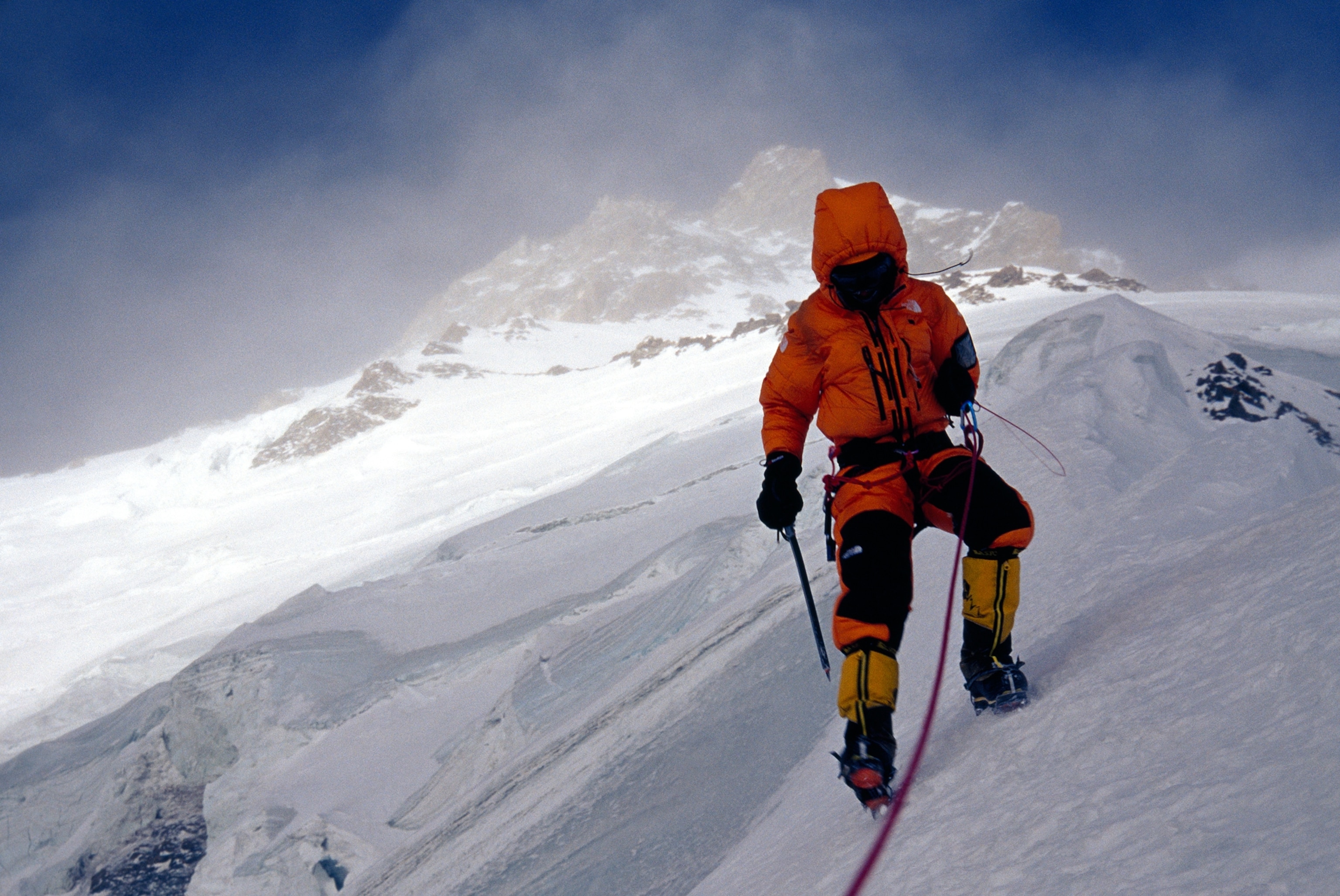 A climber ascends a steep slope of Nanga Parbat in stormy conditions.