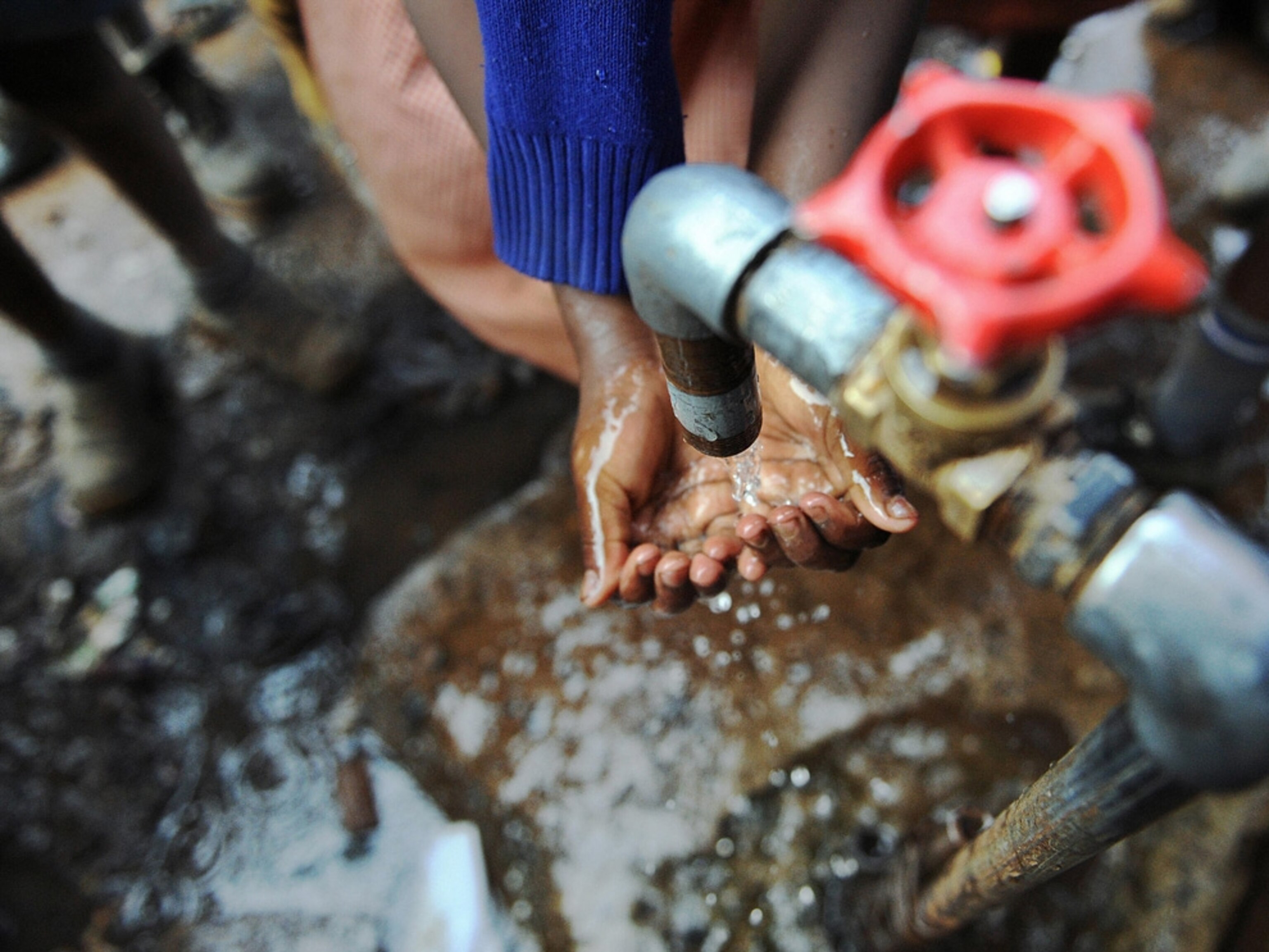 Hands under a water pump