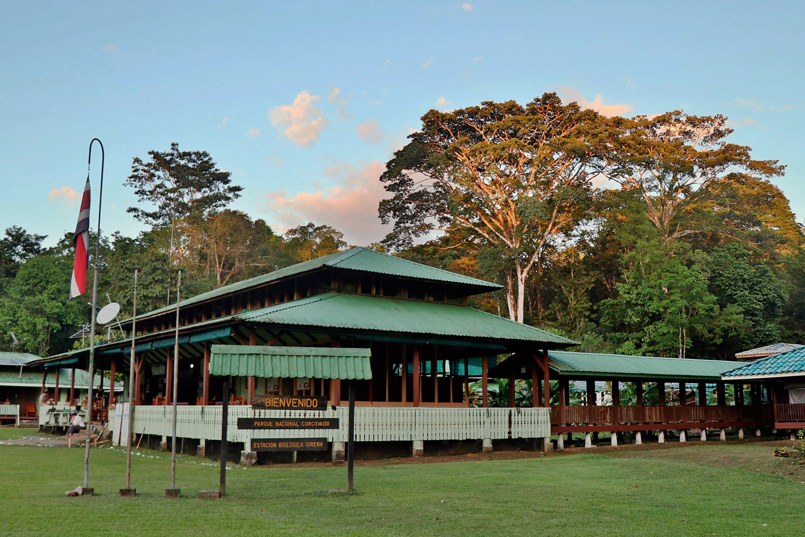 A bungalow ranger station on a grass field with a jungle bordering the house.